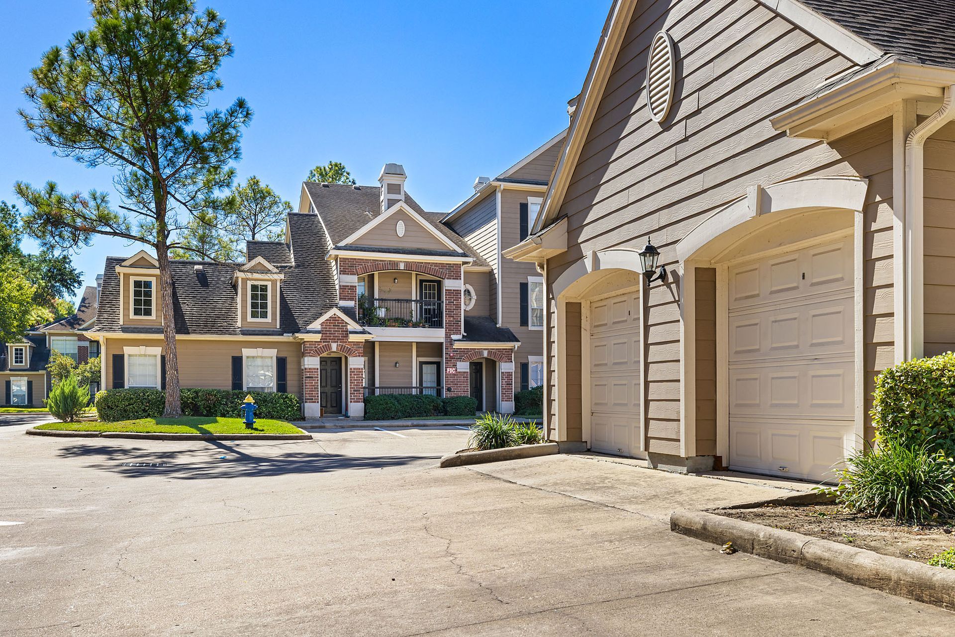 Exterior view of a multi-unit apartment community with attached garages and landscaped entry.