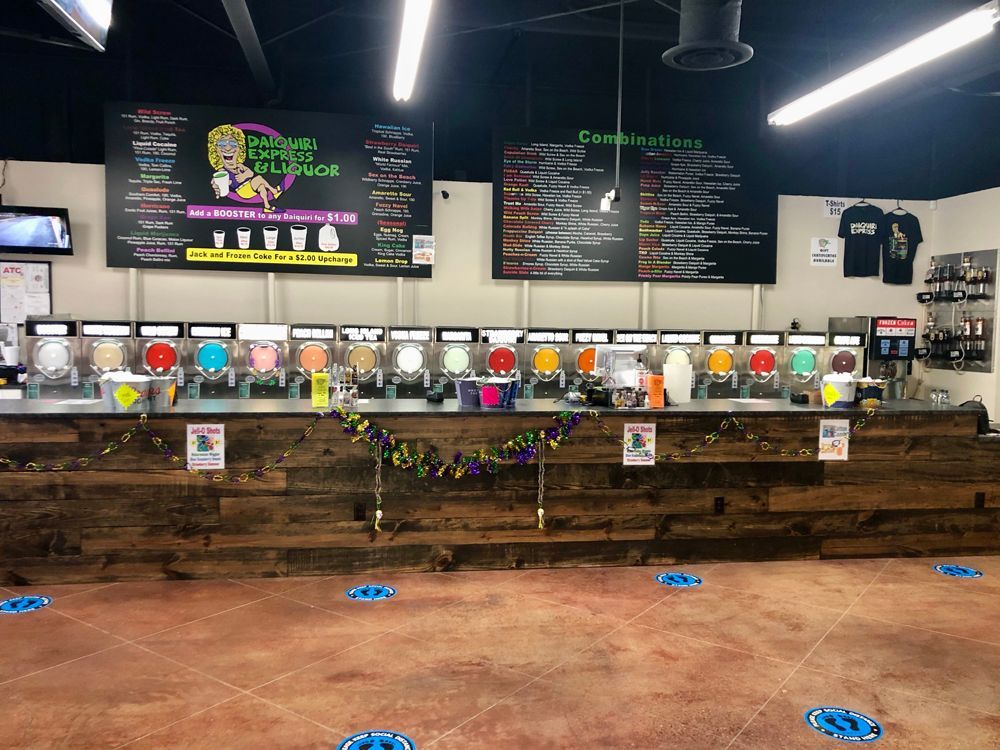 A beverage bar with a variety of colorful frozen drinks and menu boards.