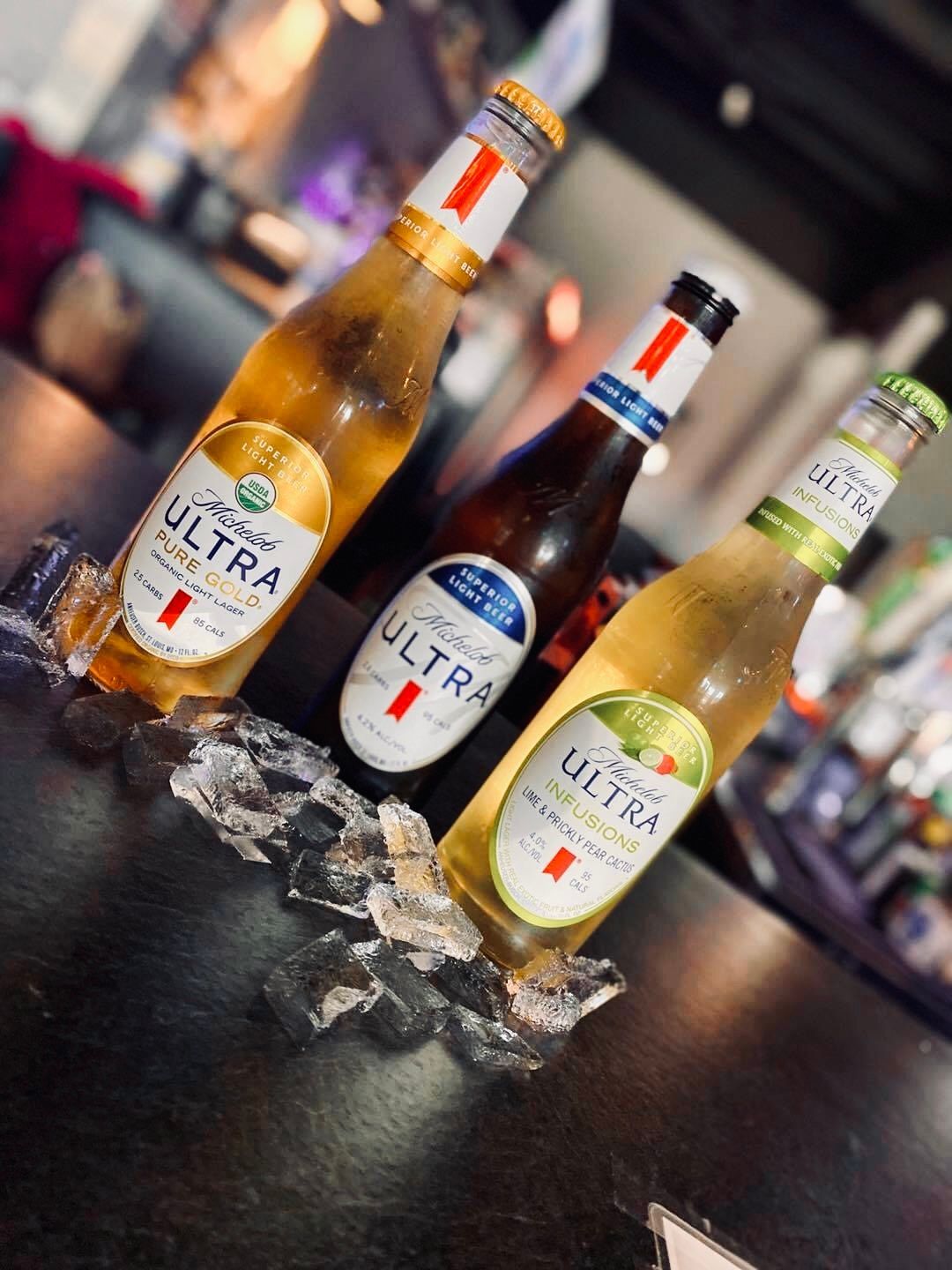 Three Michelob Ultra beer bottles in ice.