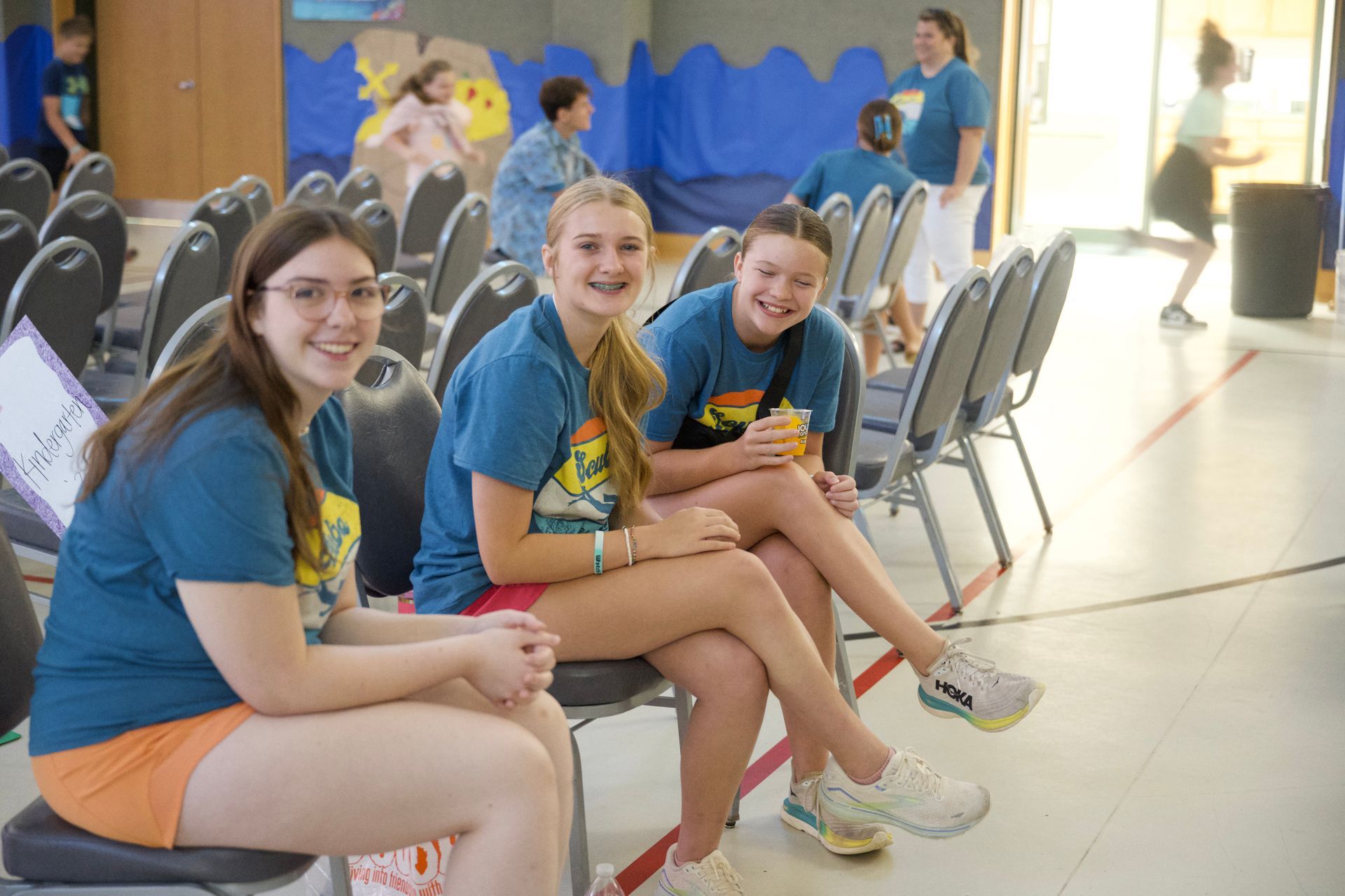 A group of young girls are sitting in chairs in a room.
