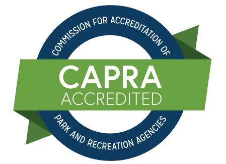 CAPRA Accredited seal featuring a blue circular border with text and a green banner reading 