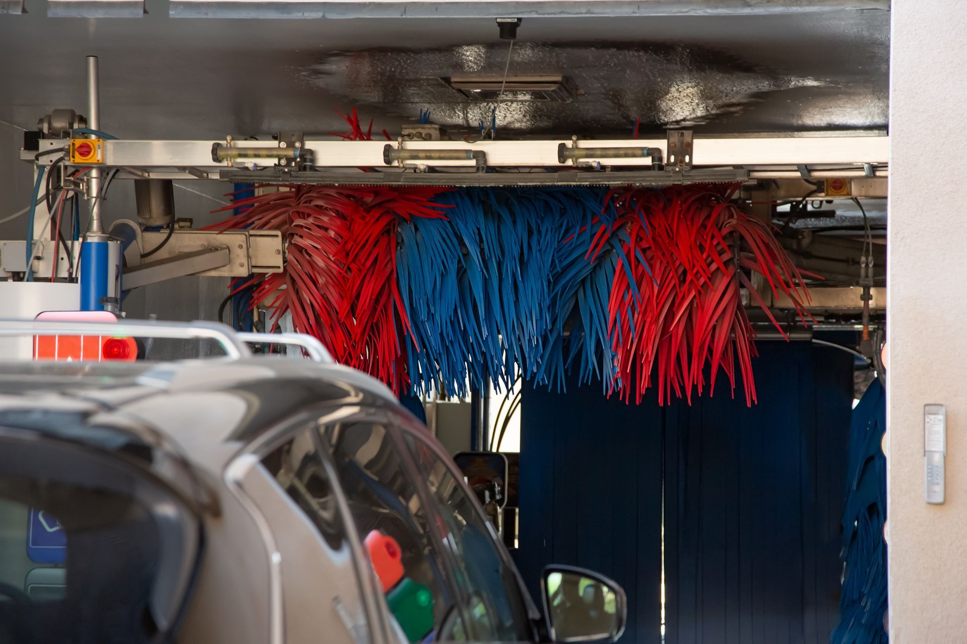 A car is going through a car wash with red and blue brushes.