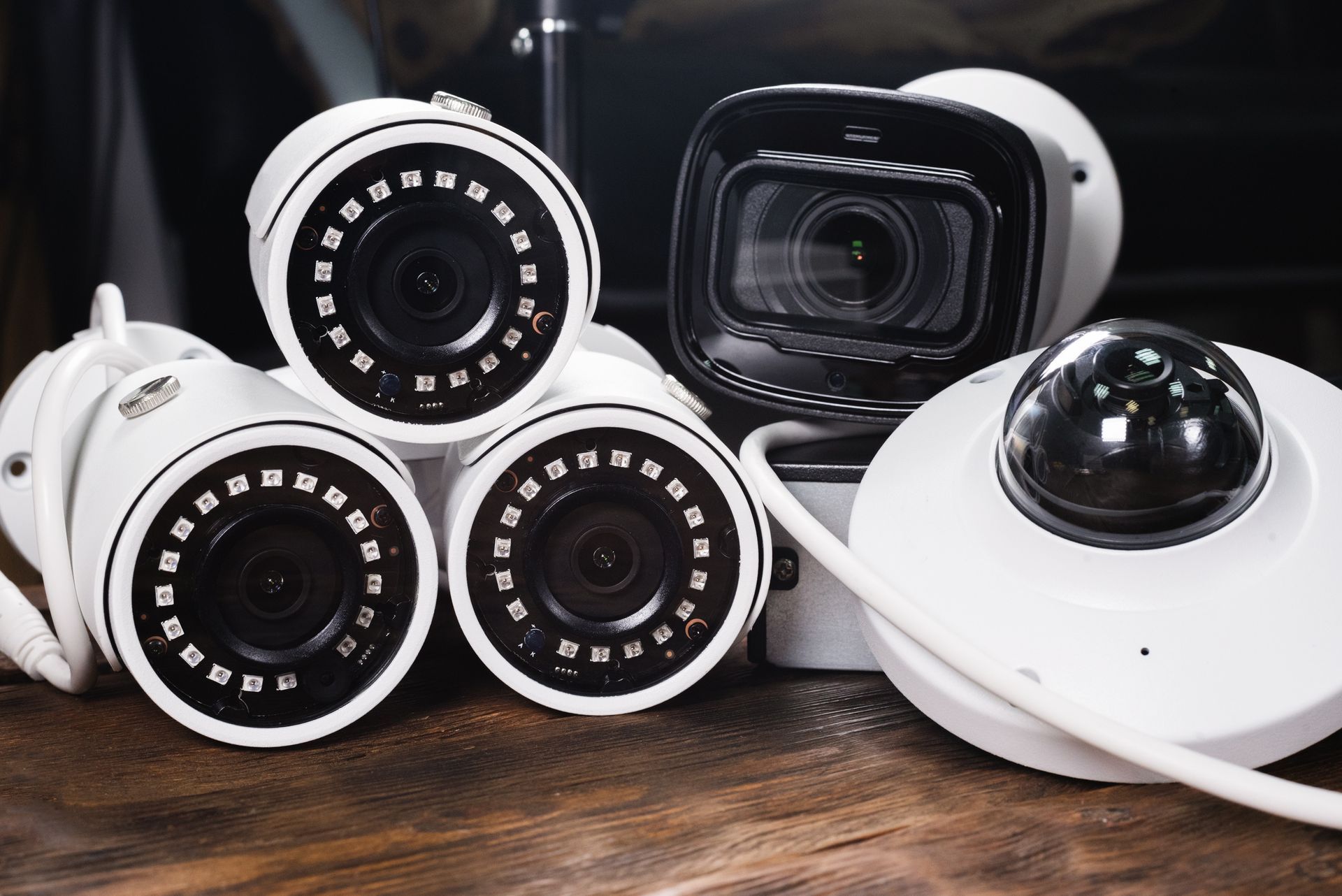 A group of security cameras sitting on top of each other on a wooden table.