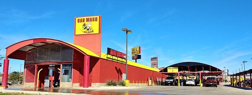 A red and yellow car wash with cars parked in front of it.