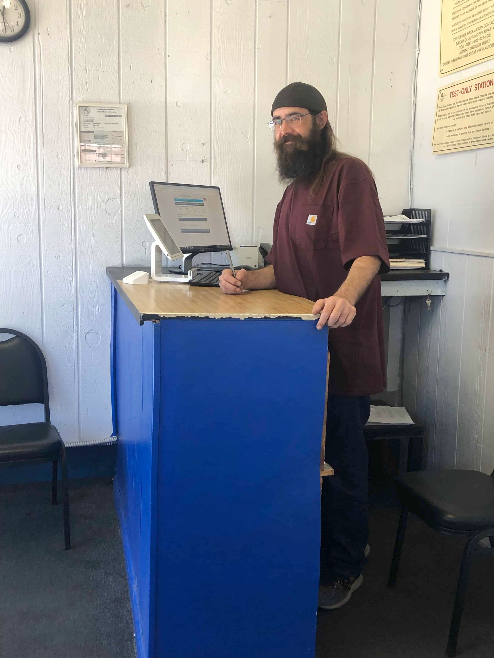 A man with a beard is standing behind a blue counter