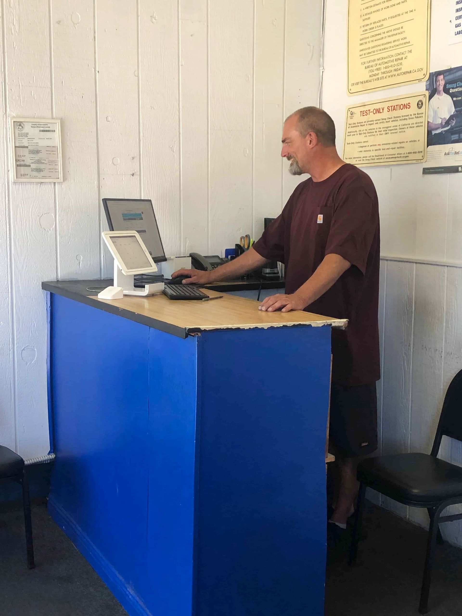 A man standing behind a blue counter with a computer on it