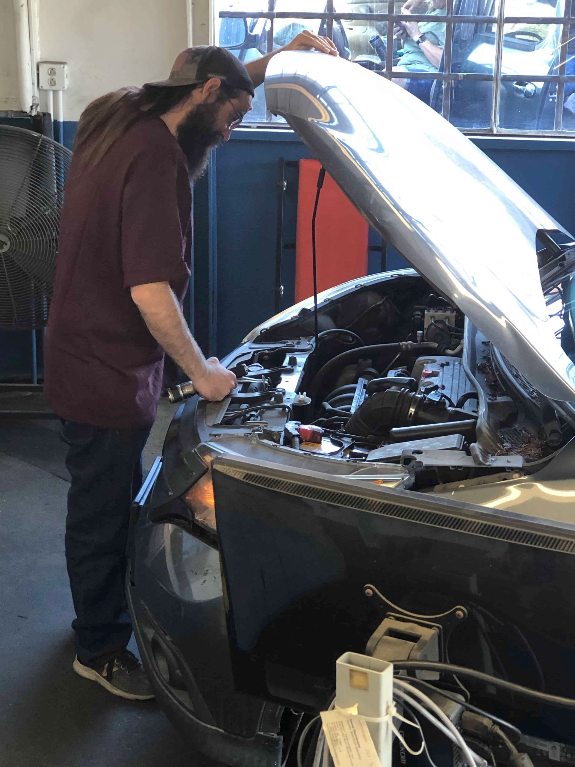 A man is working on a car with the hood open