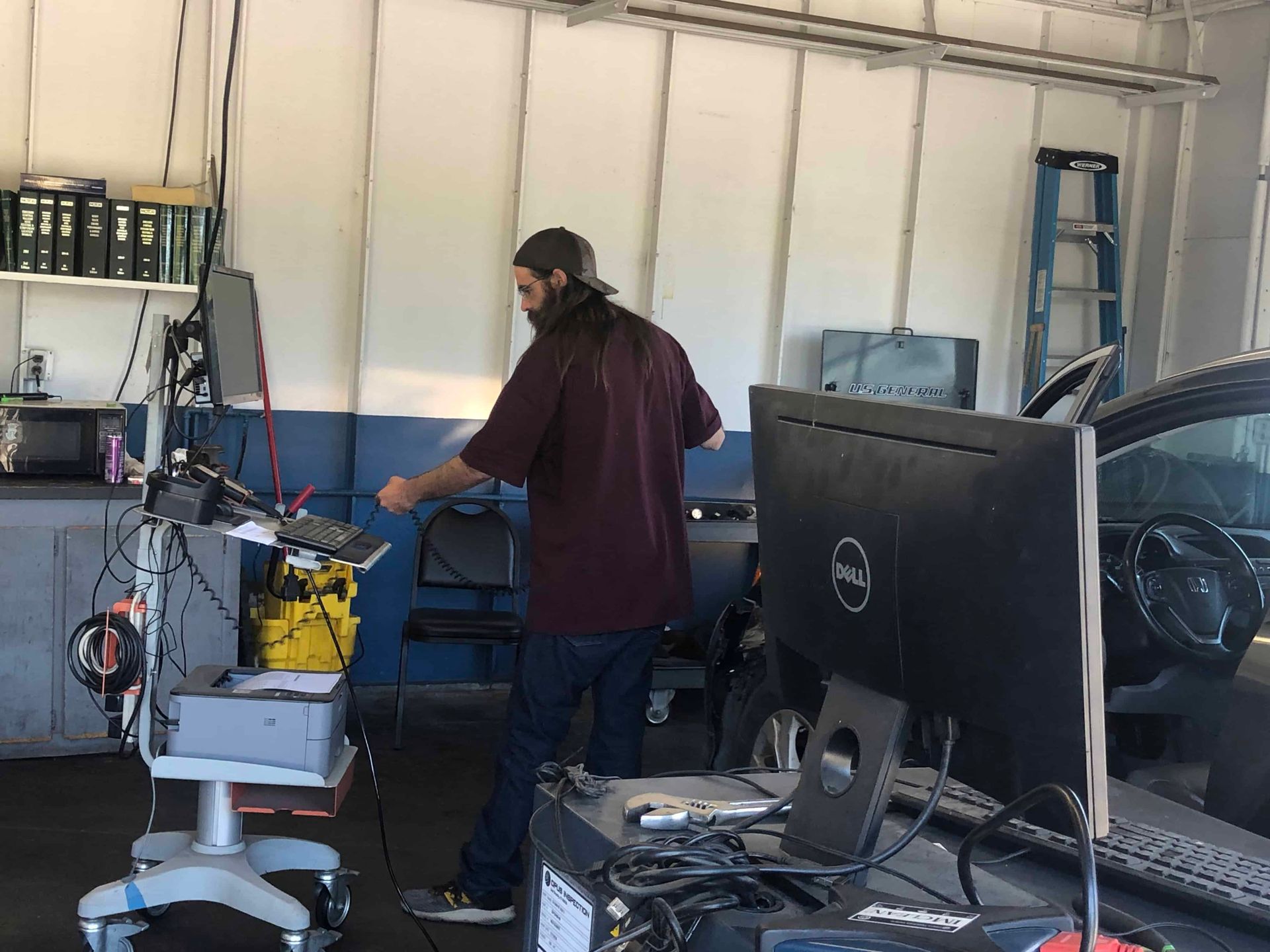 A man is standing in front of a dell computer in a garage.