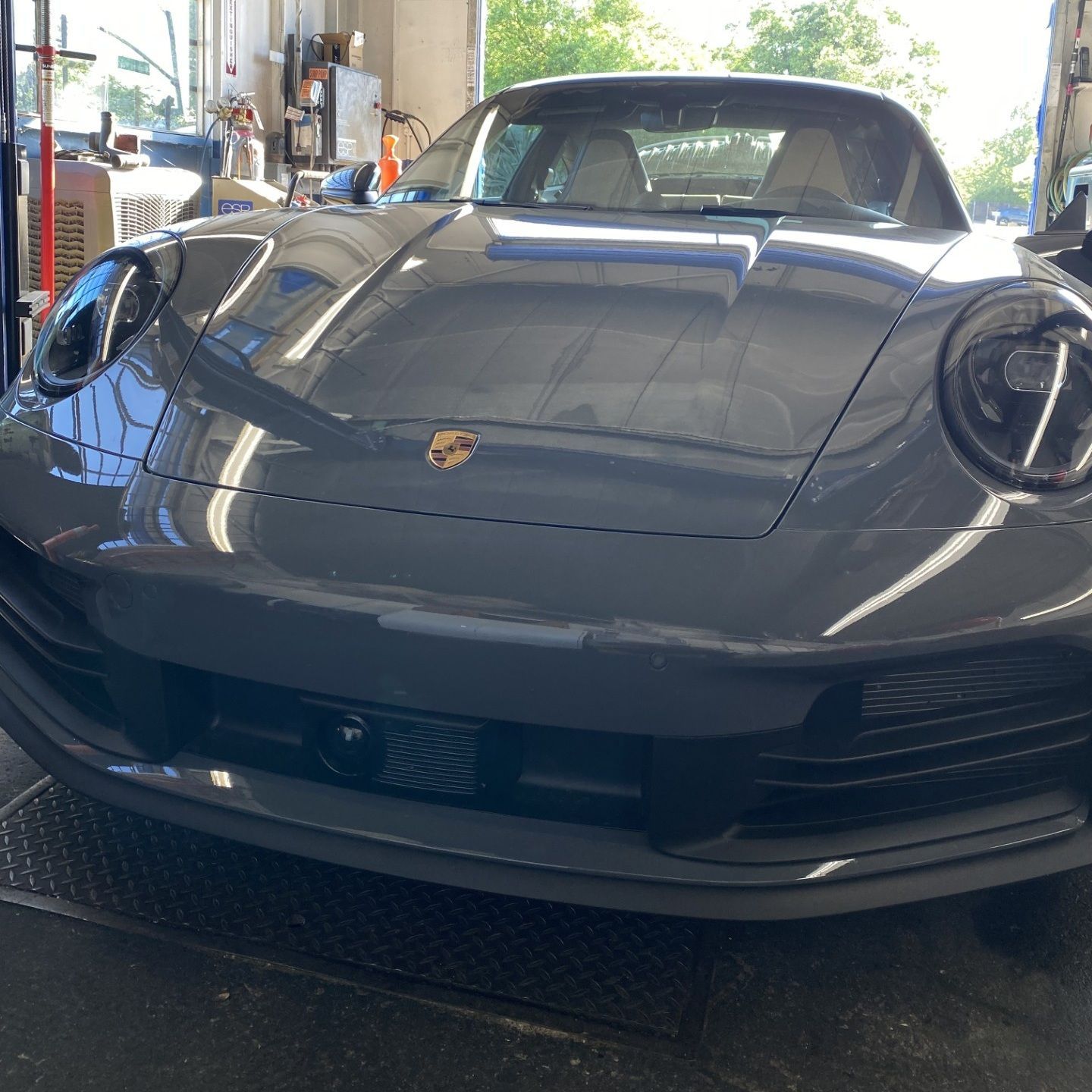 Dark gray Porsche sports car viewed from the front in a garage or showroom.