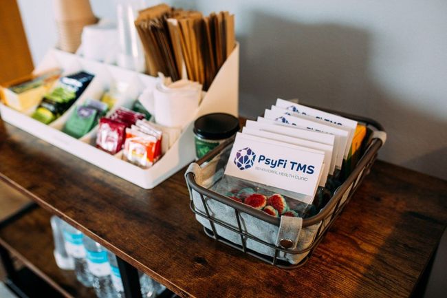A wooden table with a basket filled with tea bags and a tray of straws.