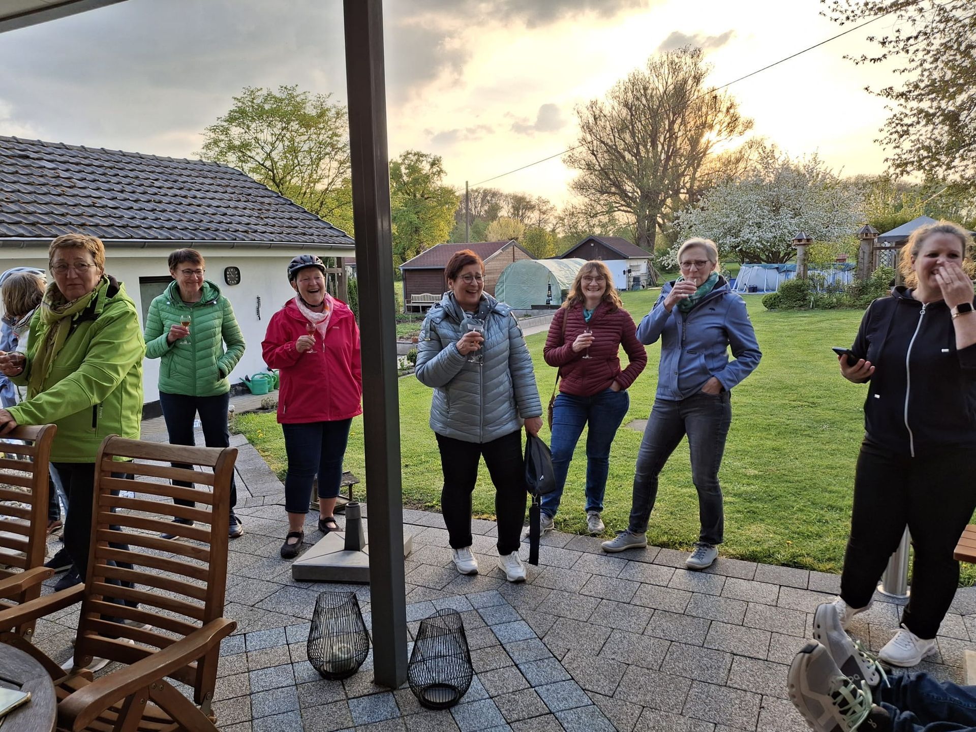 Eine Gruppe Frauen steht auf einer Terrasse und trinkt Wein.