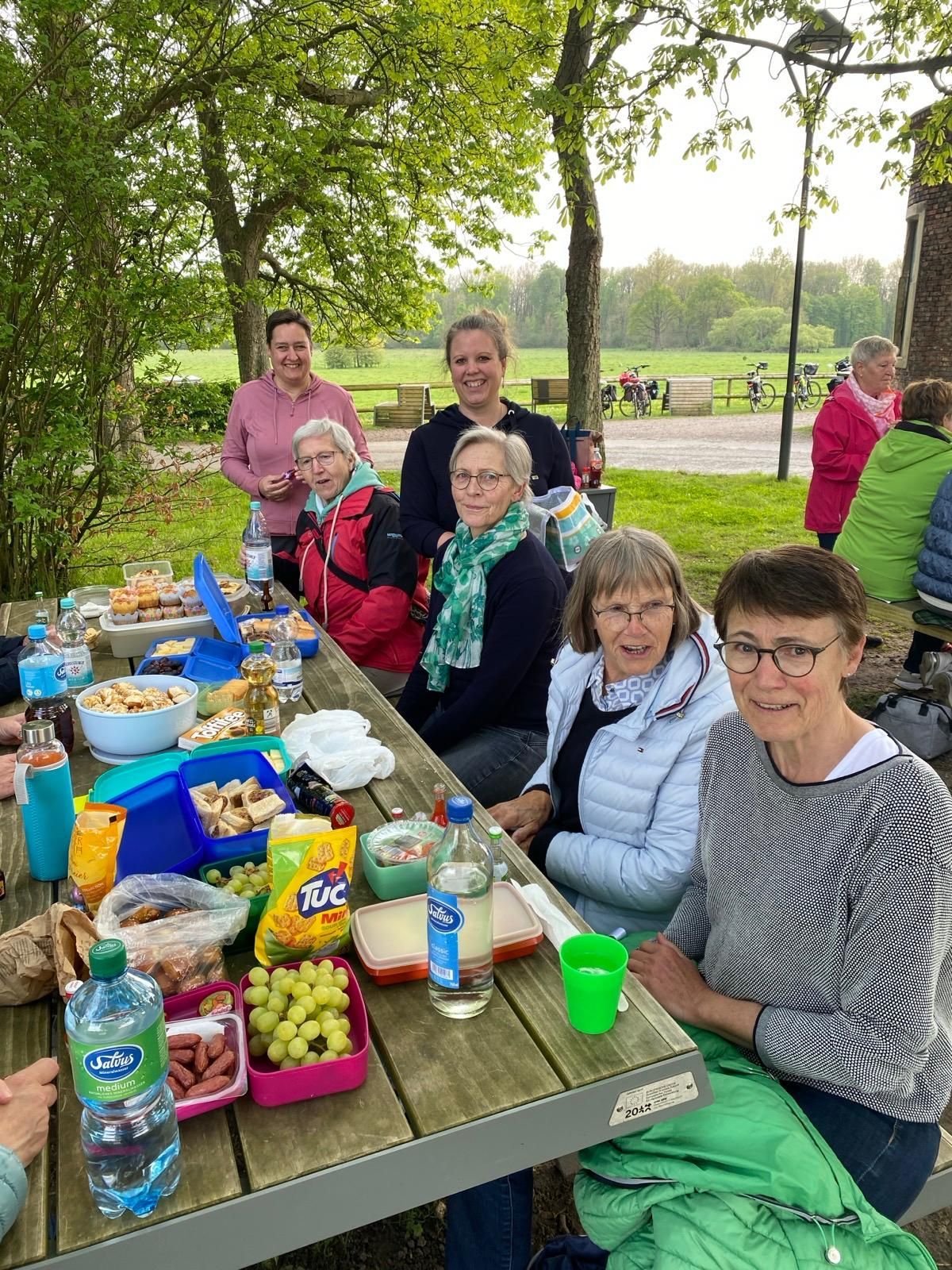 Eine Gruppe von Menschen sitzt an einem Picknicktisch in einem Park.