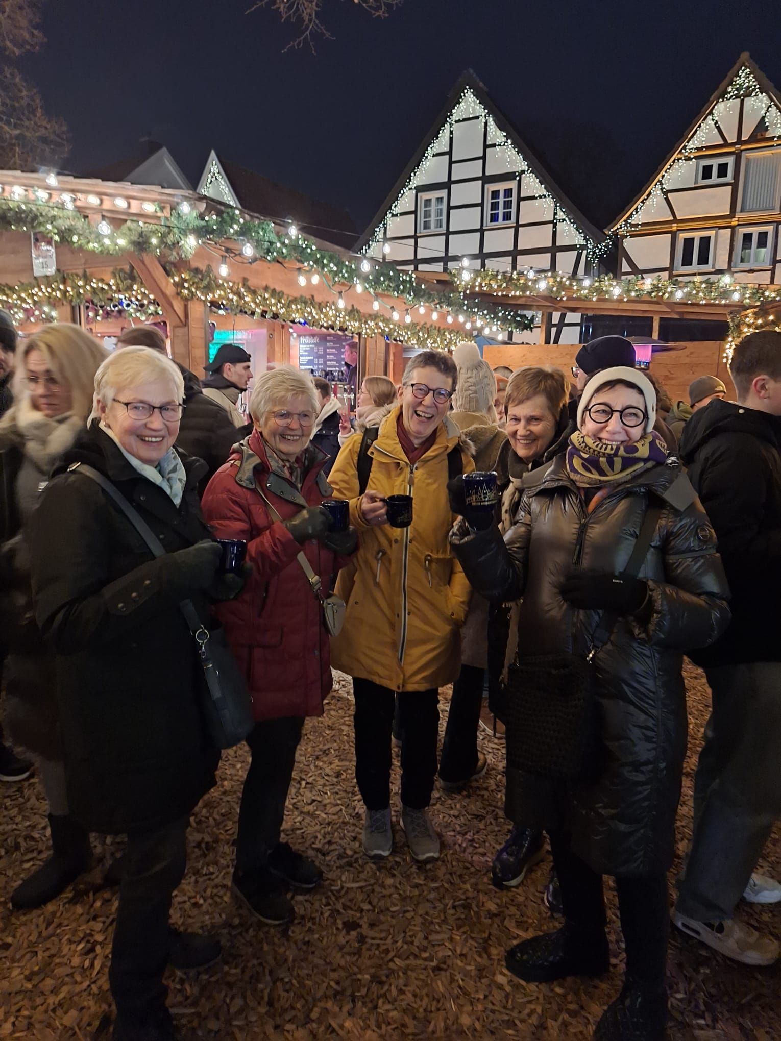 Eine Gruppe von Menschen posiert auf einem Weihnachtsmarkt für ein Foto.