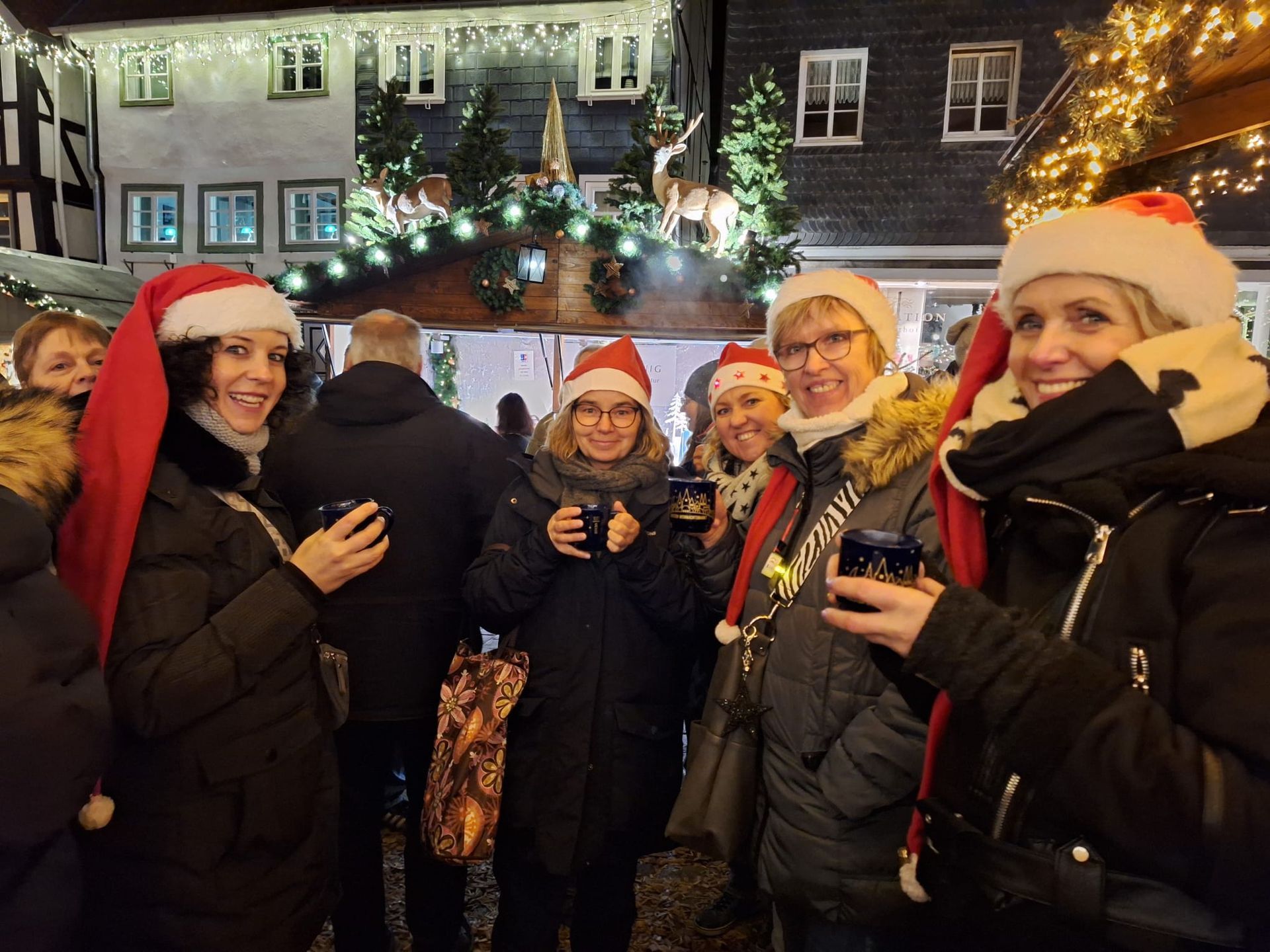 Eine Gruppe von Menschen mit Weihnachtsmannmützen steht vor einem Gebäude.