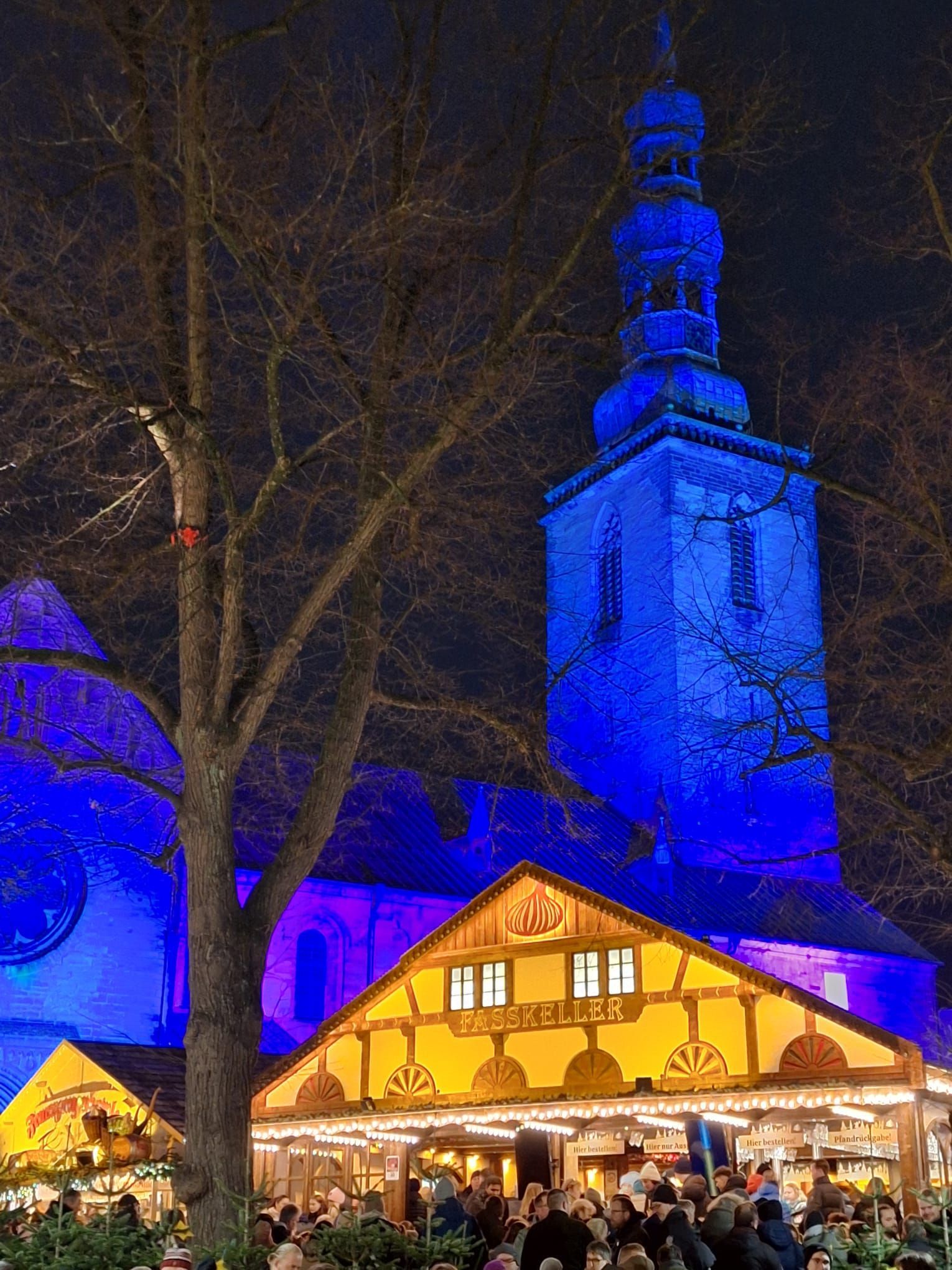 Ein Kirchturm wird nachts mit blauem Licht beleuchtet.