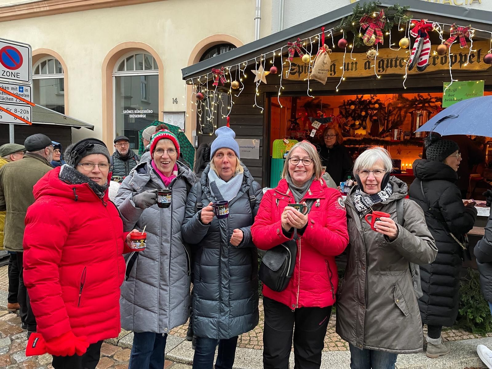 Eine Gruppe von Frauen posiert vor einem Weihnachtsmarkt für ein Foto.