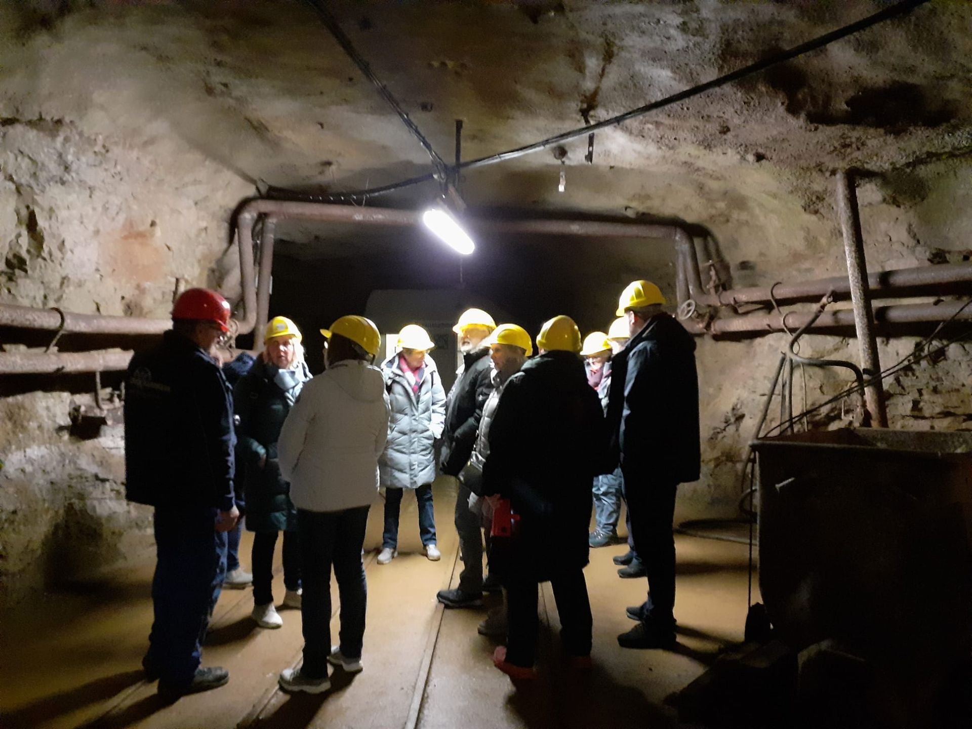 Eine Gruppe von Menschen mit Schutzhelmen steht in einem dunklen Tunnel.