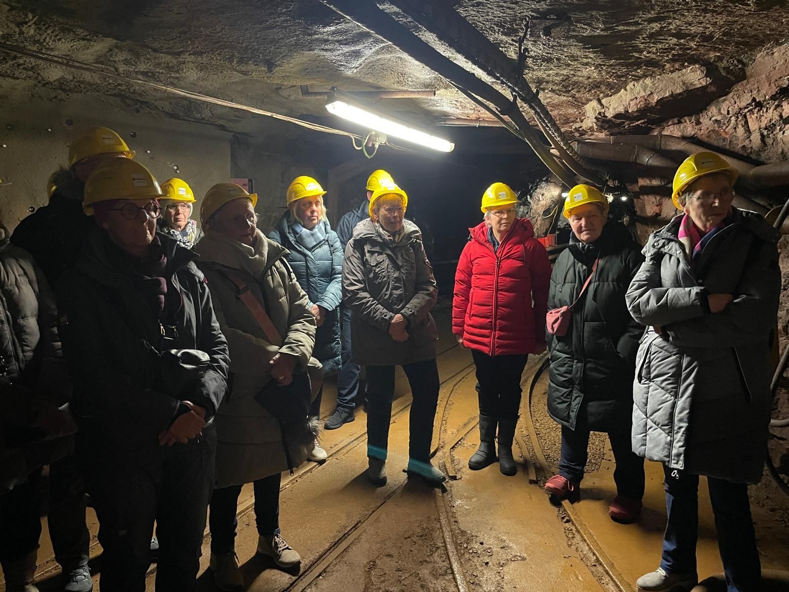 Eine Gruppe von Menschen mit Schutzhelmen steht in einem dunklen Tunnel.