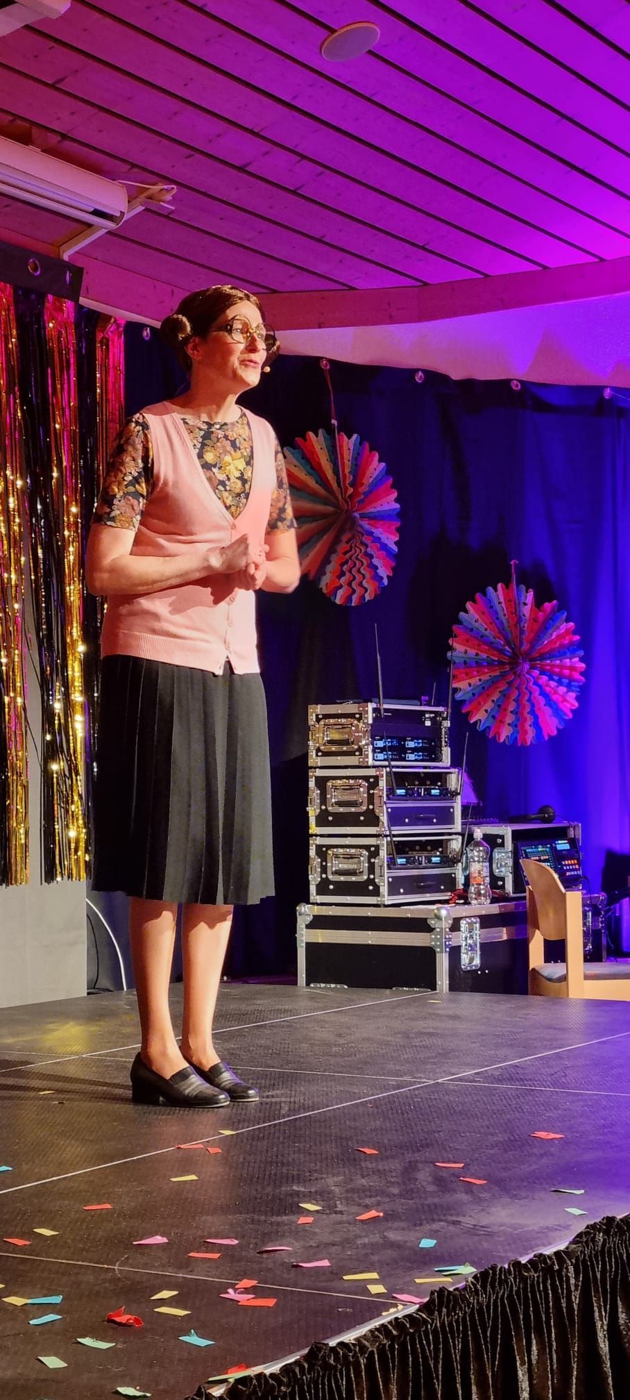 Eine Frau steht auf einer Bühne vor einem violetten Vorhang.