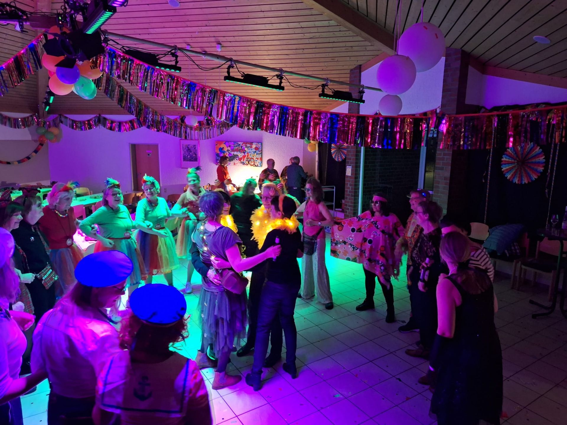 Eine Gruppe von Menschen tanzt in einem Raum mit violettem Licht.
