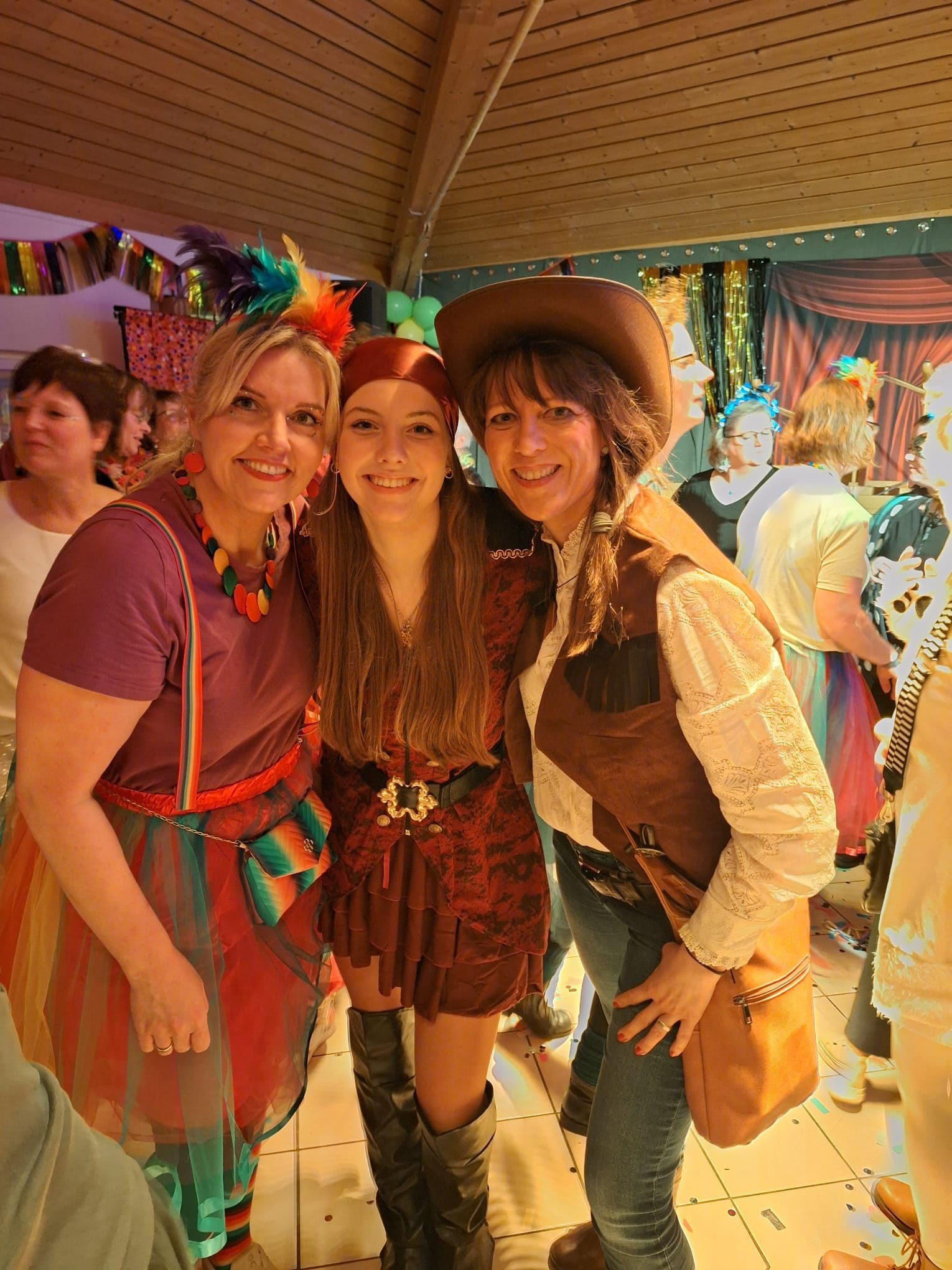 Drei kostümierte Frauen posieren auf einer Party für ein Foto.