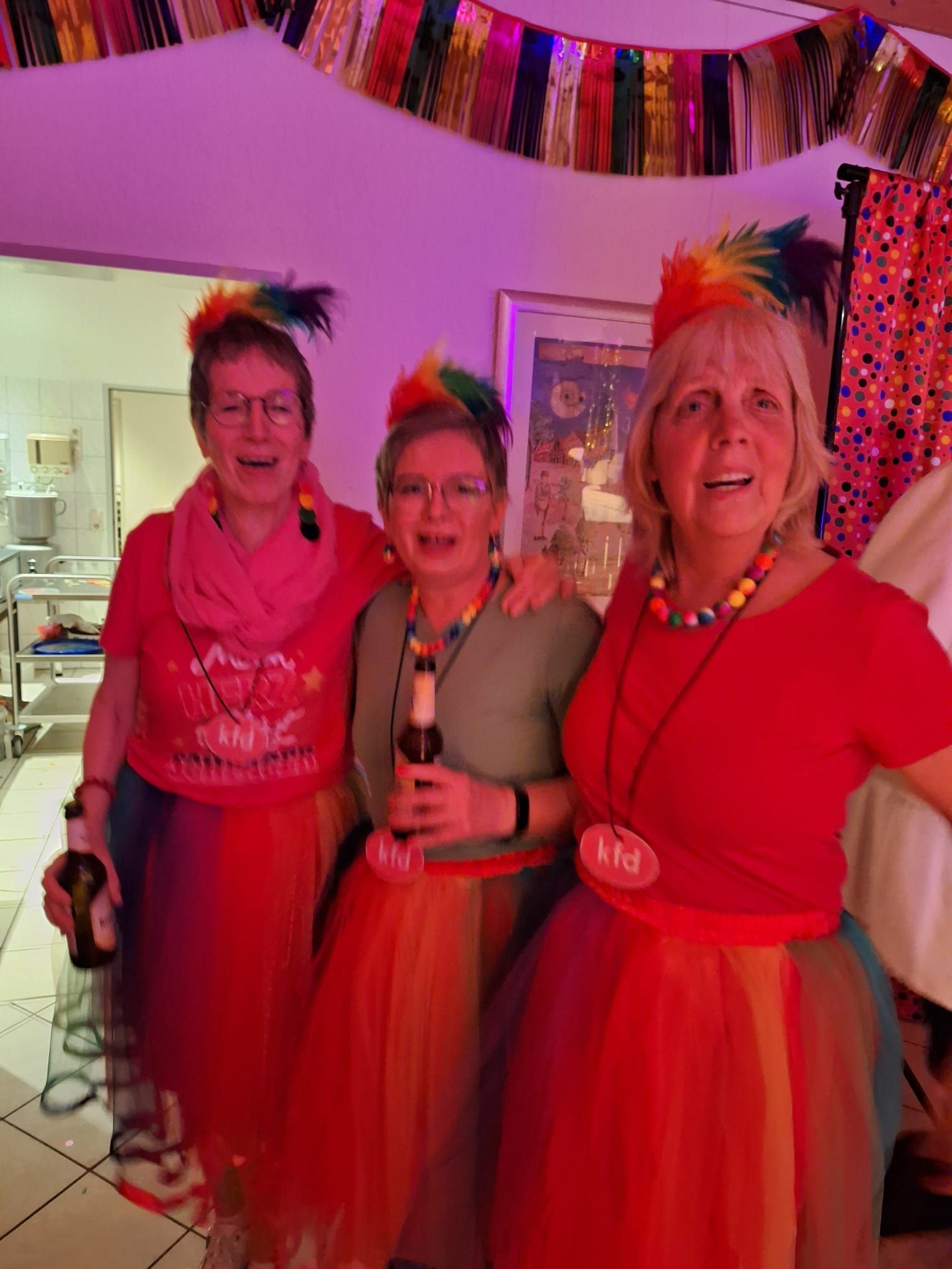 Drei Frauen in farbenfrohen Kostümen posieren für ein Foto.