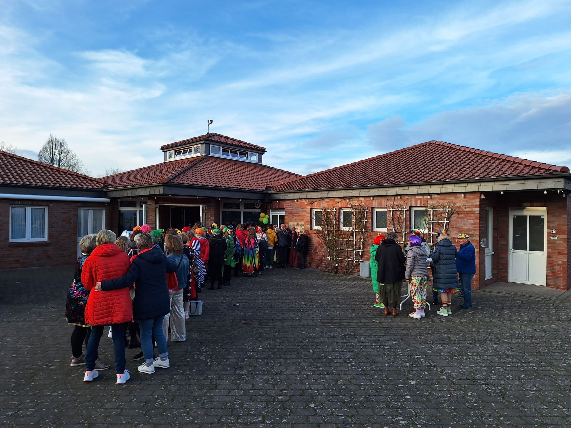 Eine Gruppe von Menschen steht vor einem Backsteingebäude.