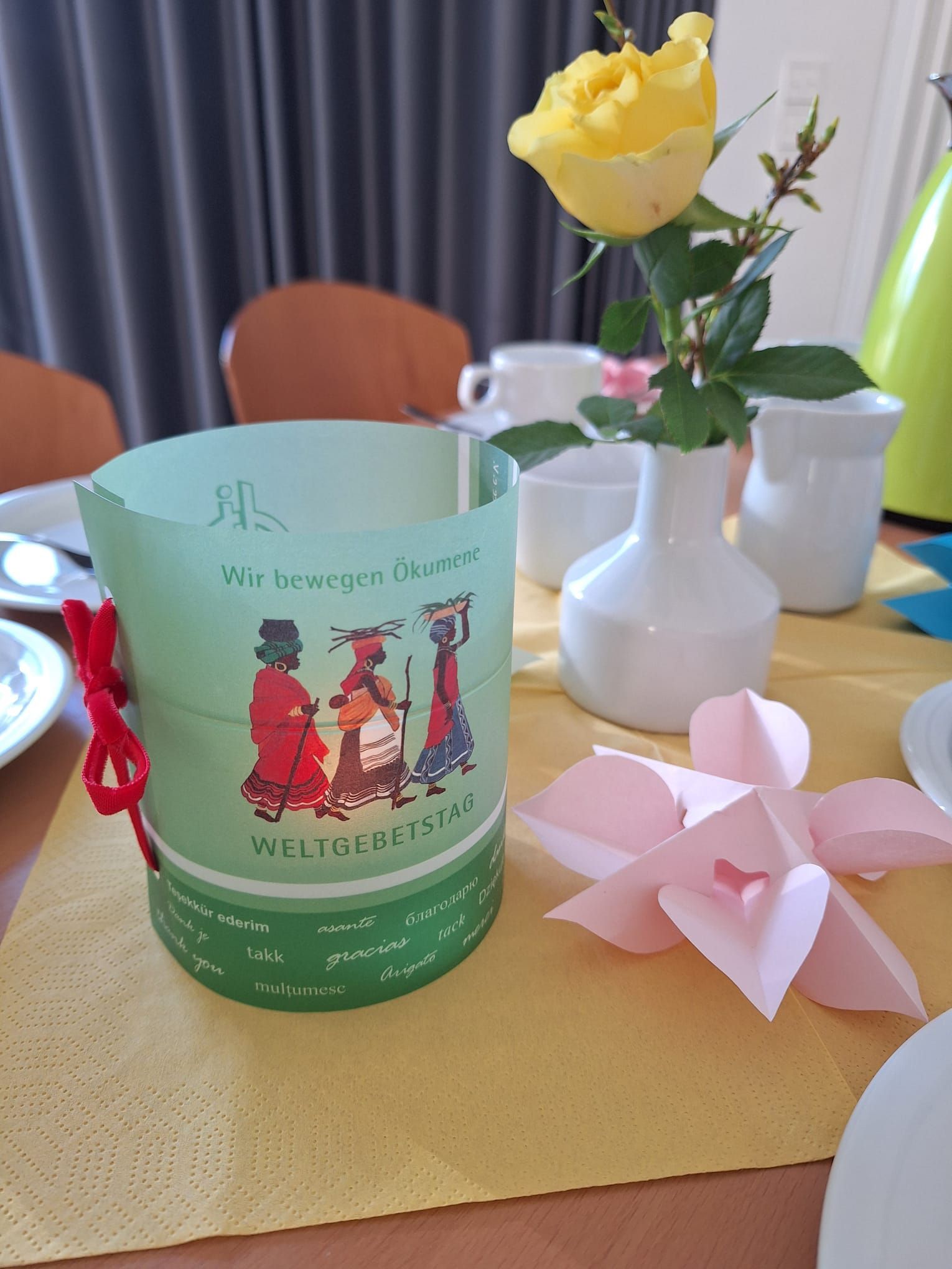 Ein Tisch mit einer Blumenvase und einer Papierblume darauf.