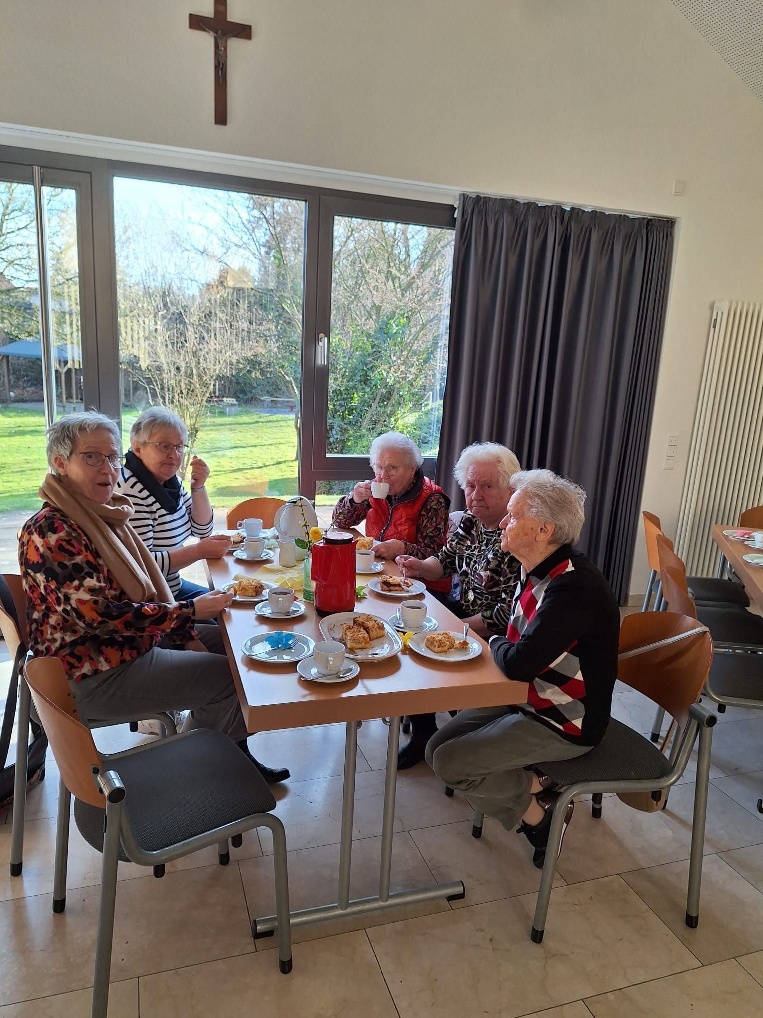 Eine Gruppe älterer Frauen sitzt um einen Tisch herum und isst.