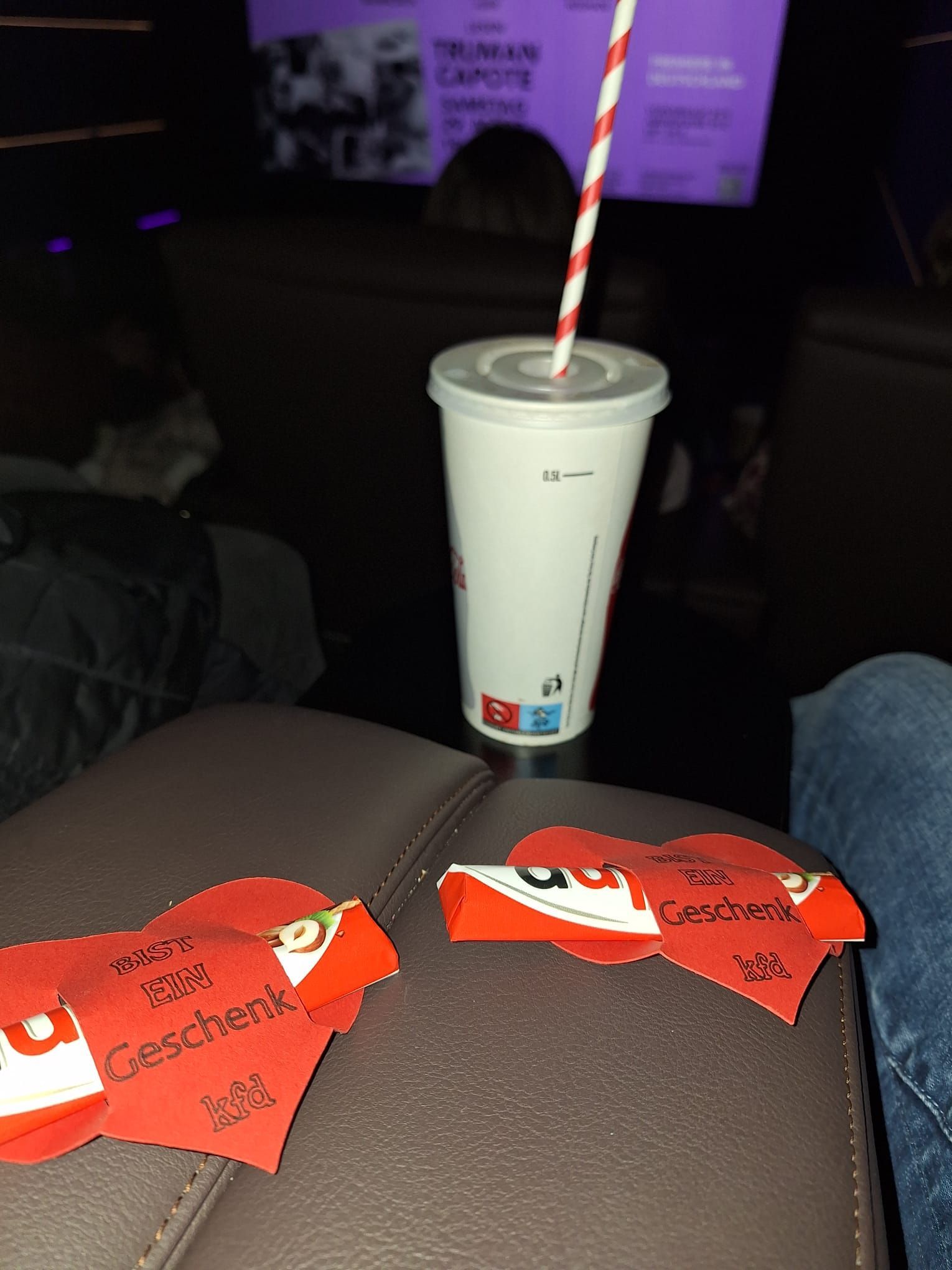 Eine Tasse mit einem rot-weißen Strohhalm steht auf einem Sofa