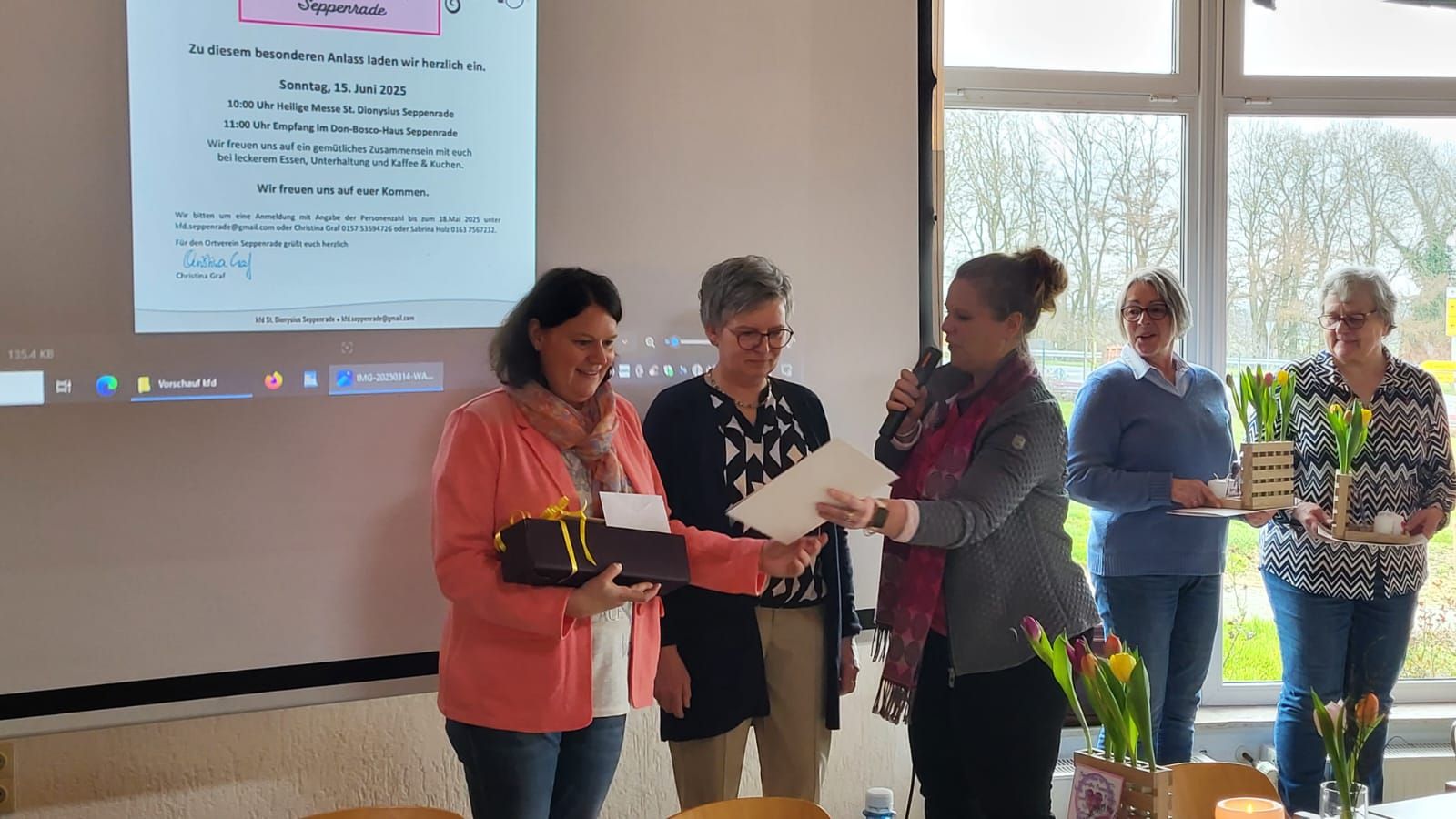 Eine Gruppe von Frauen steht vor einer Projektionsleinwand.