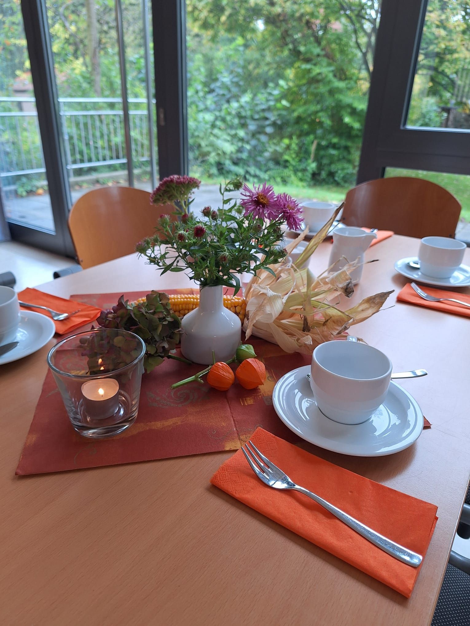 Ein für eine Mahlzeit gedeckter Tisch mit einer Vase mit Blumen darauf.