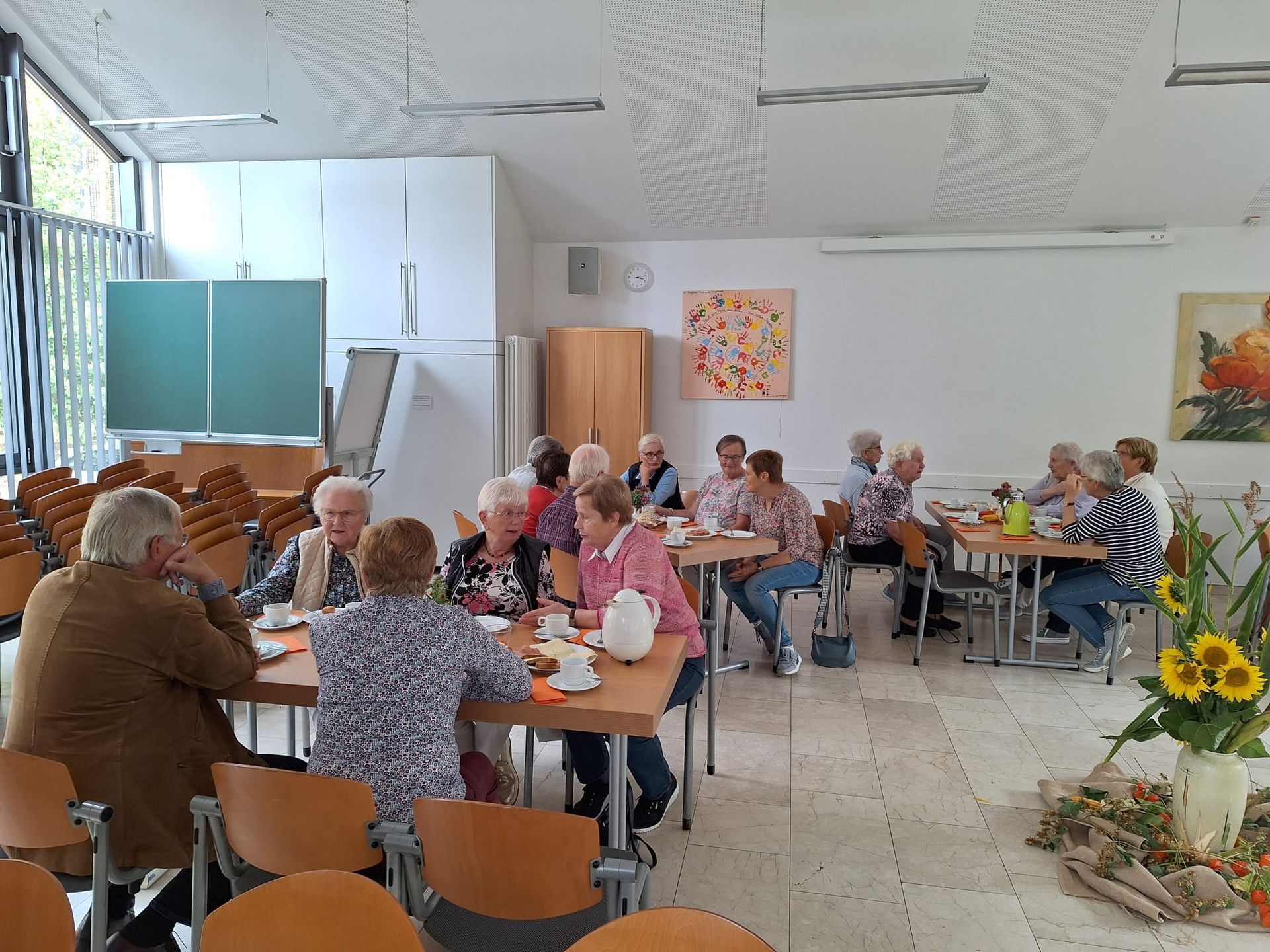 Eine Gruppe von Menschen sitzt in einem Raum an Tischen.