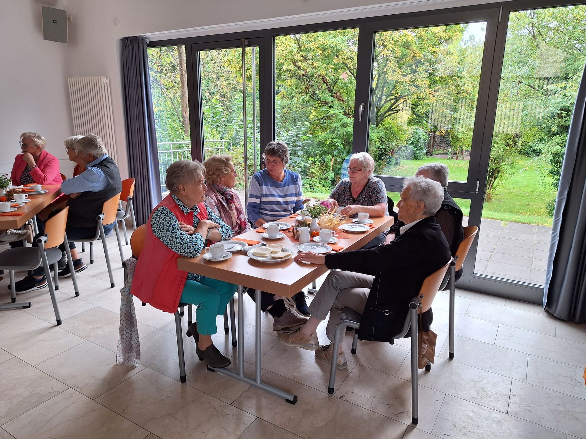 Eine Gruppe von Menschen sitzt in einem Raum um einen Tisch herum.
