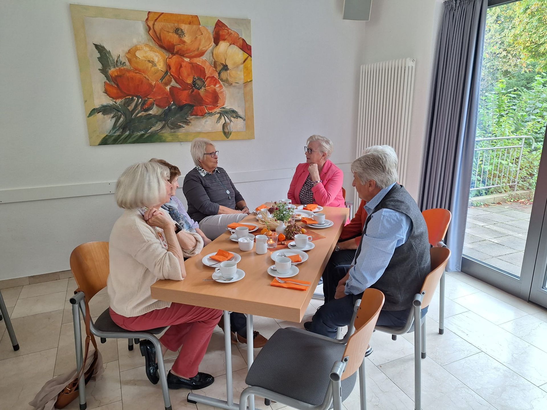 Eine Gruppe von Menschen sitzt in einem Raum um einen Tisch herum.