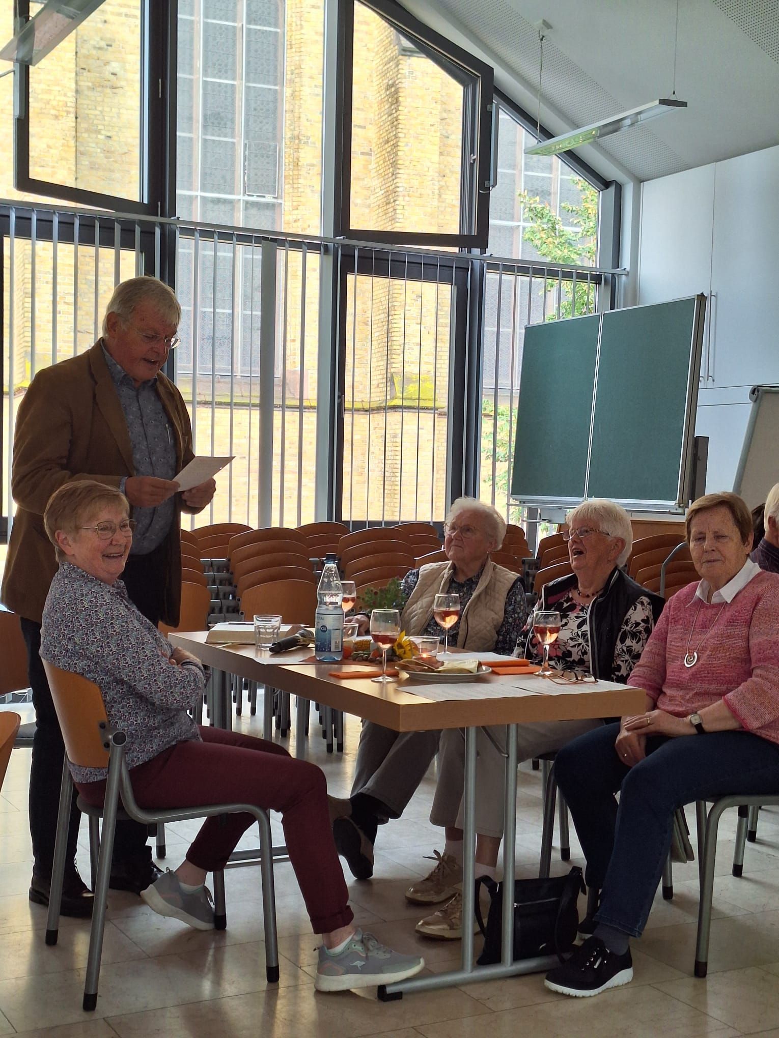Eine Gruppe von Menschen sitzt in einem Raum um einen Tisch herum.