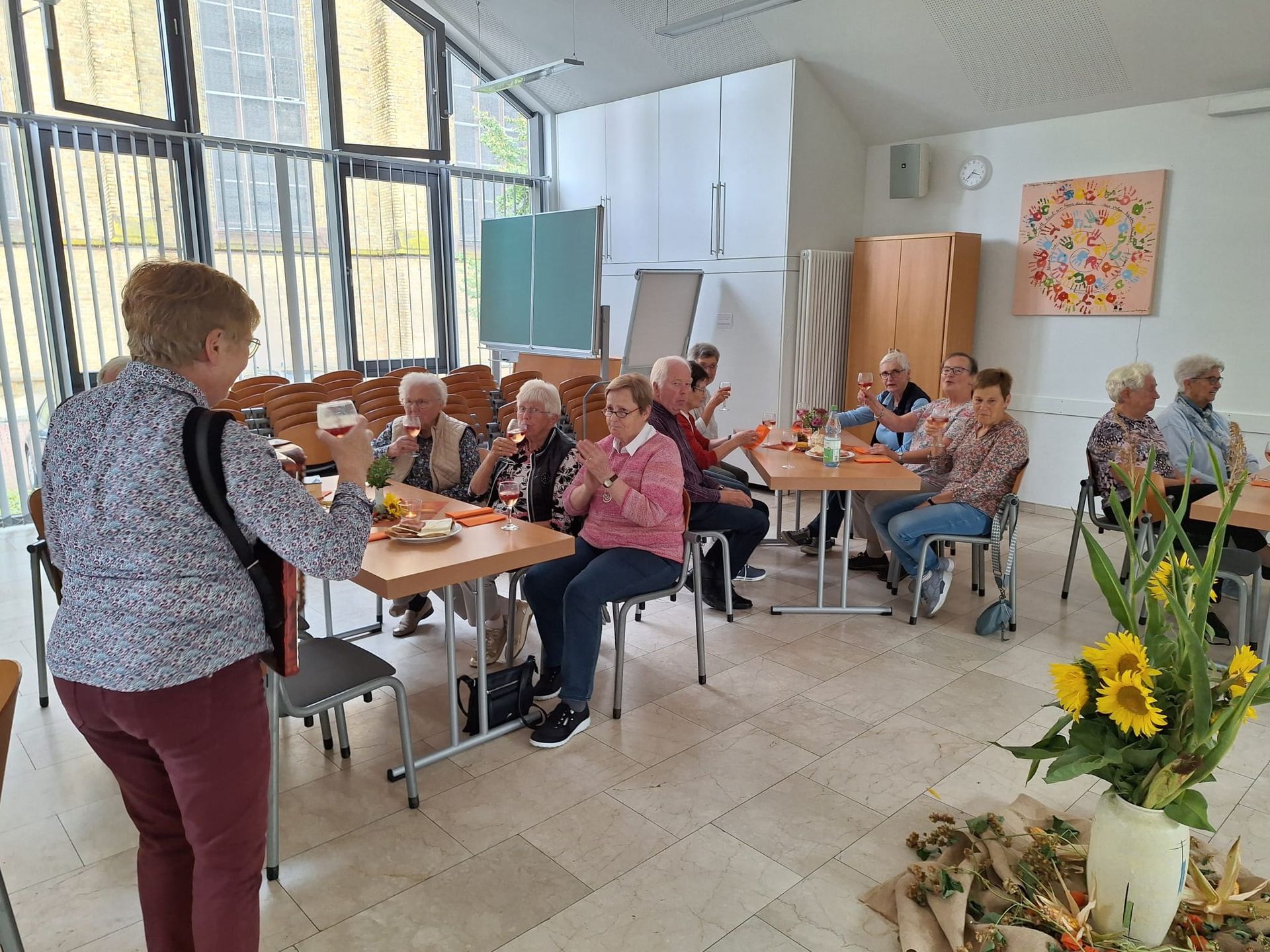 Eine Frau macht ein Foto von einer Gruppe von Menschen, die an Tischen sitzen.