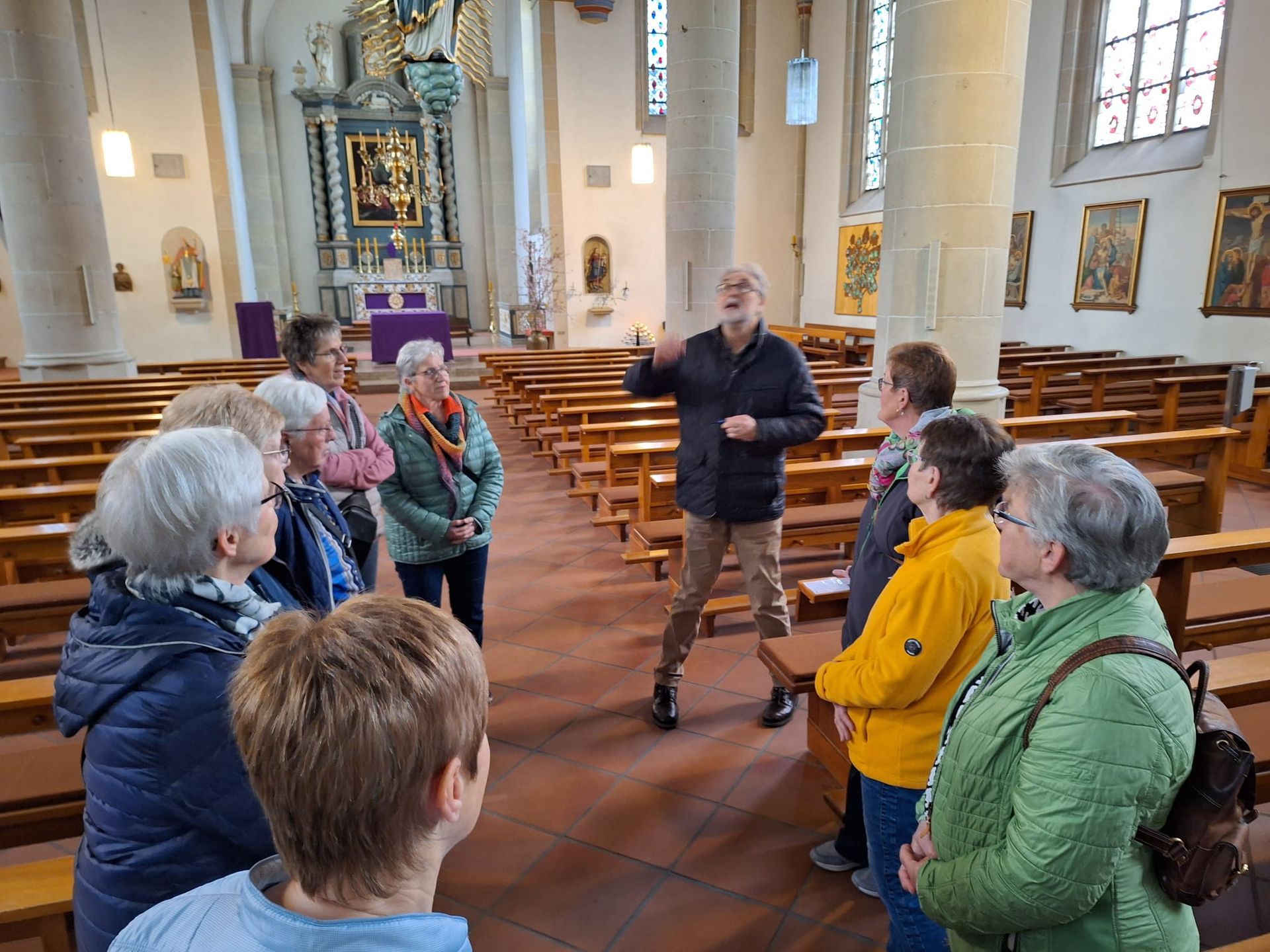 Eine Gruppe von Menschen steht in einer Kirche und unterhält sich mit einem Mann.
