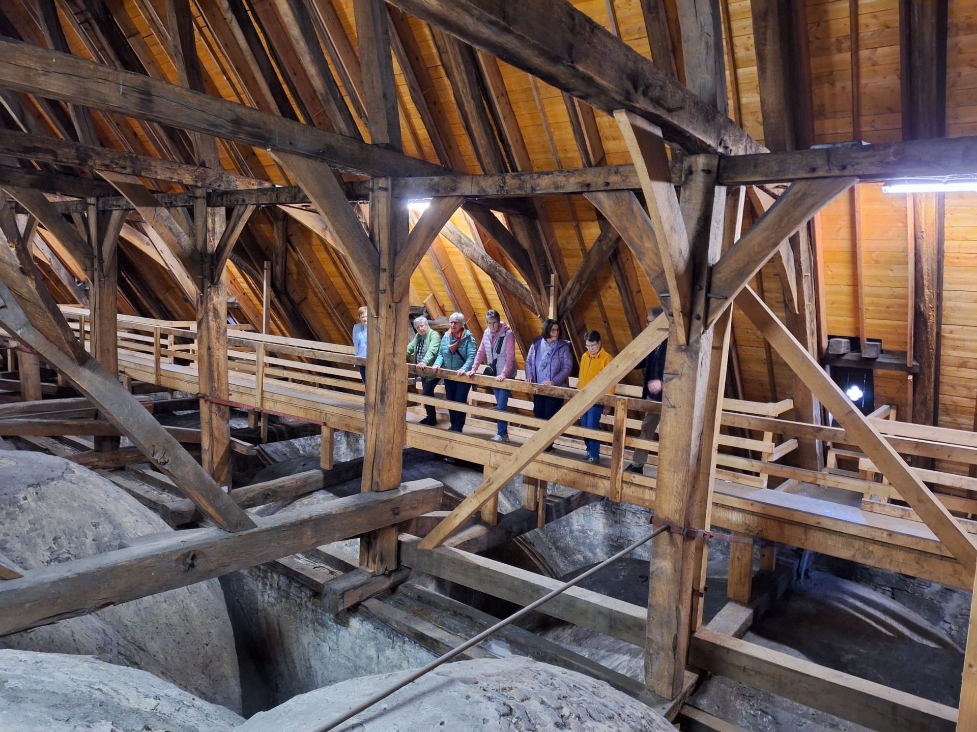 Eine Gruppe von Menschen steht auf einer Holzbrücke in einem Gebäude.