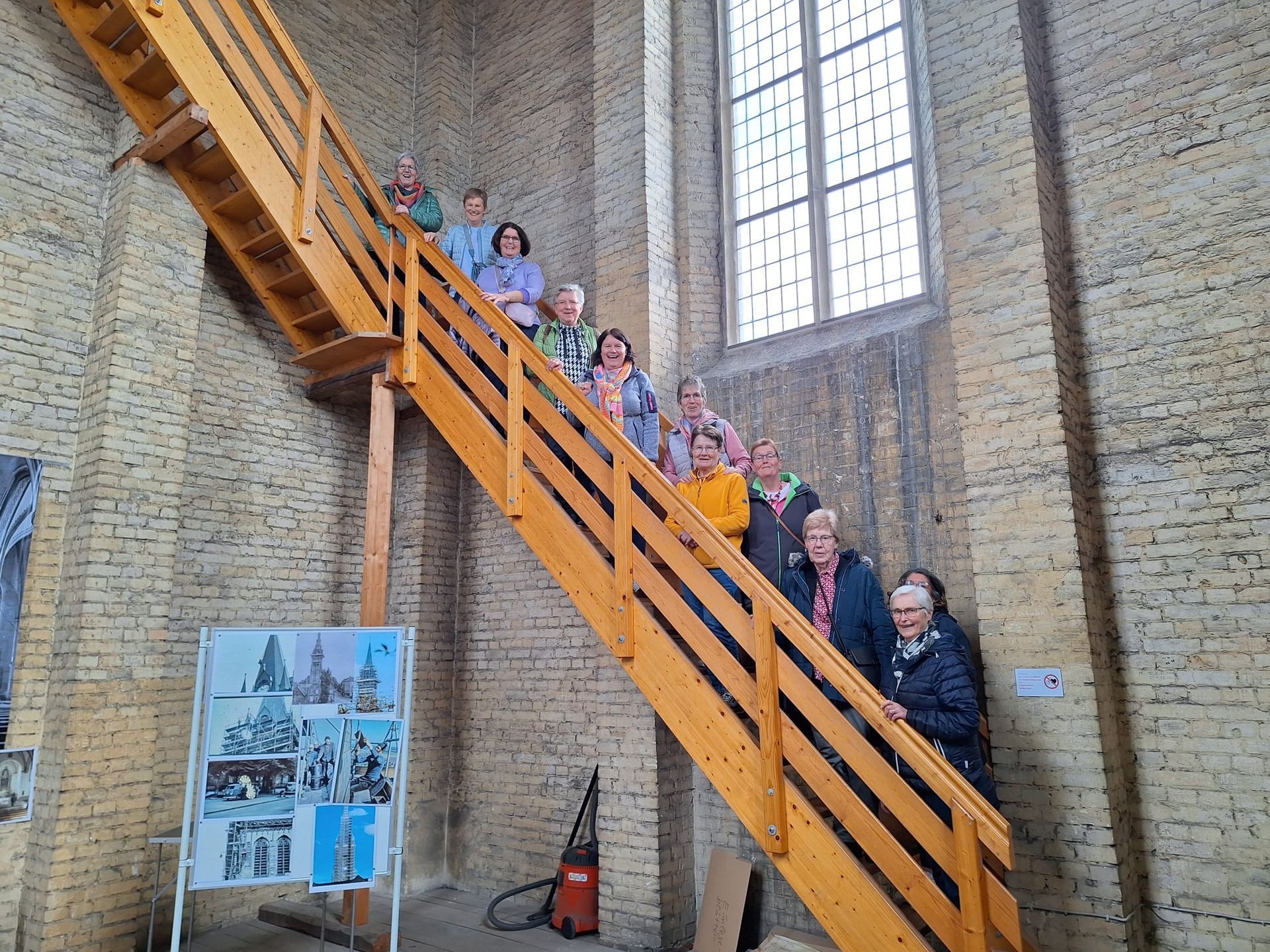 Eine Gruppe von Menschen steht auf einer Holztreppe in einer Kirche.
