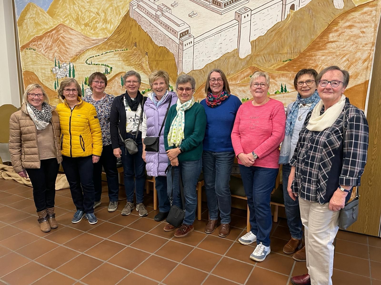 Eine Gruppe von Frauen steht nebeneinander vor einem Gemälde.
