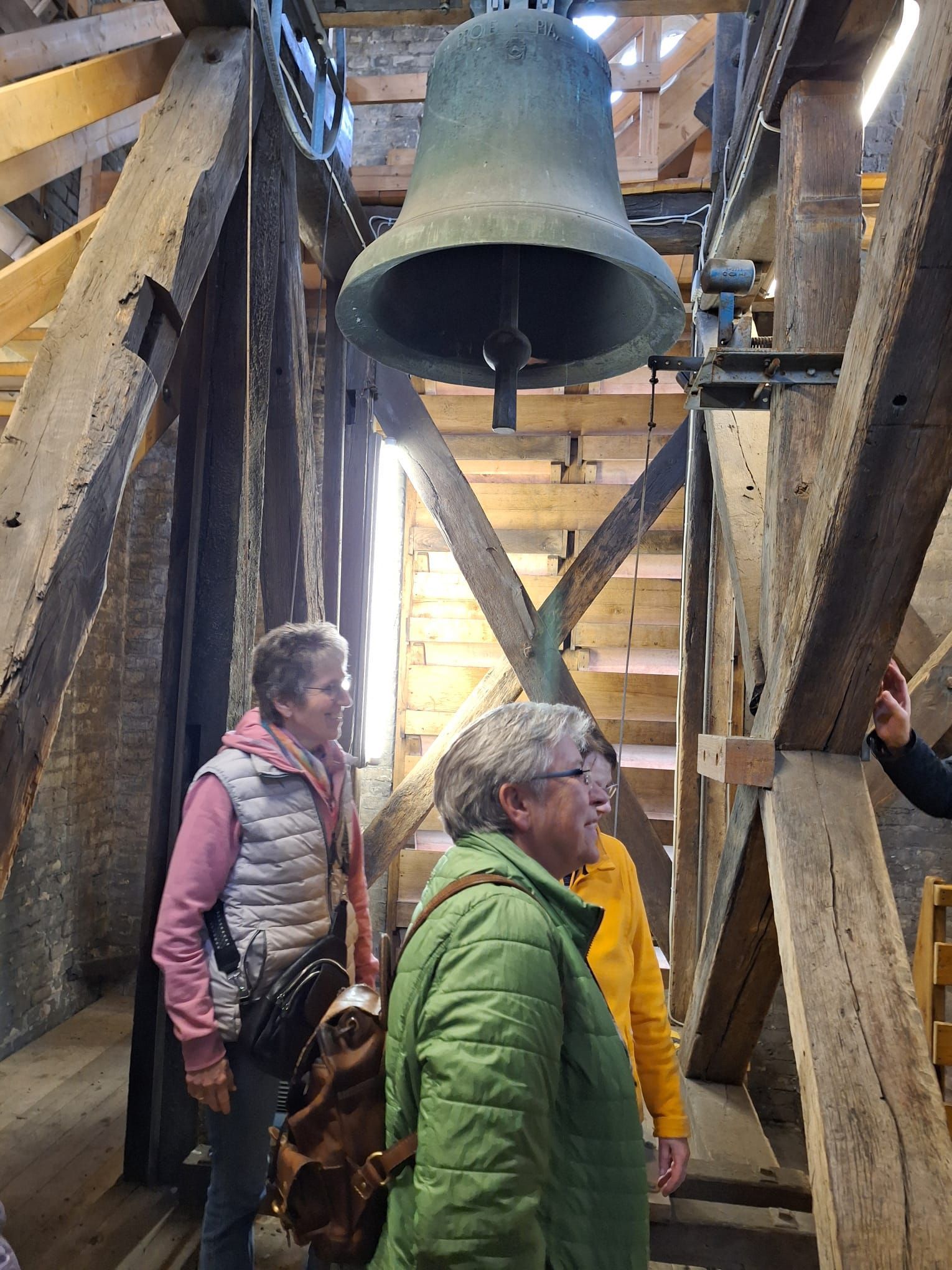 Eine Gruppe von Menschen steht vor einer großen Glocke.