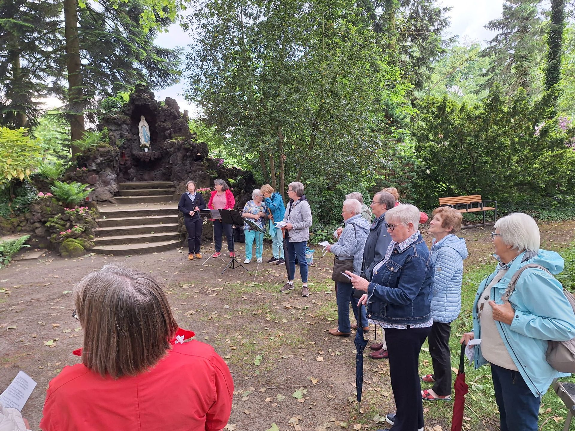 Eine Gruppe von Menschen steht in einem Park und unterhält sich.