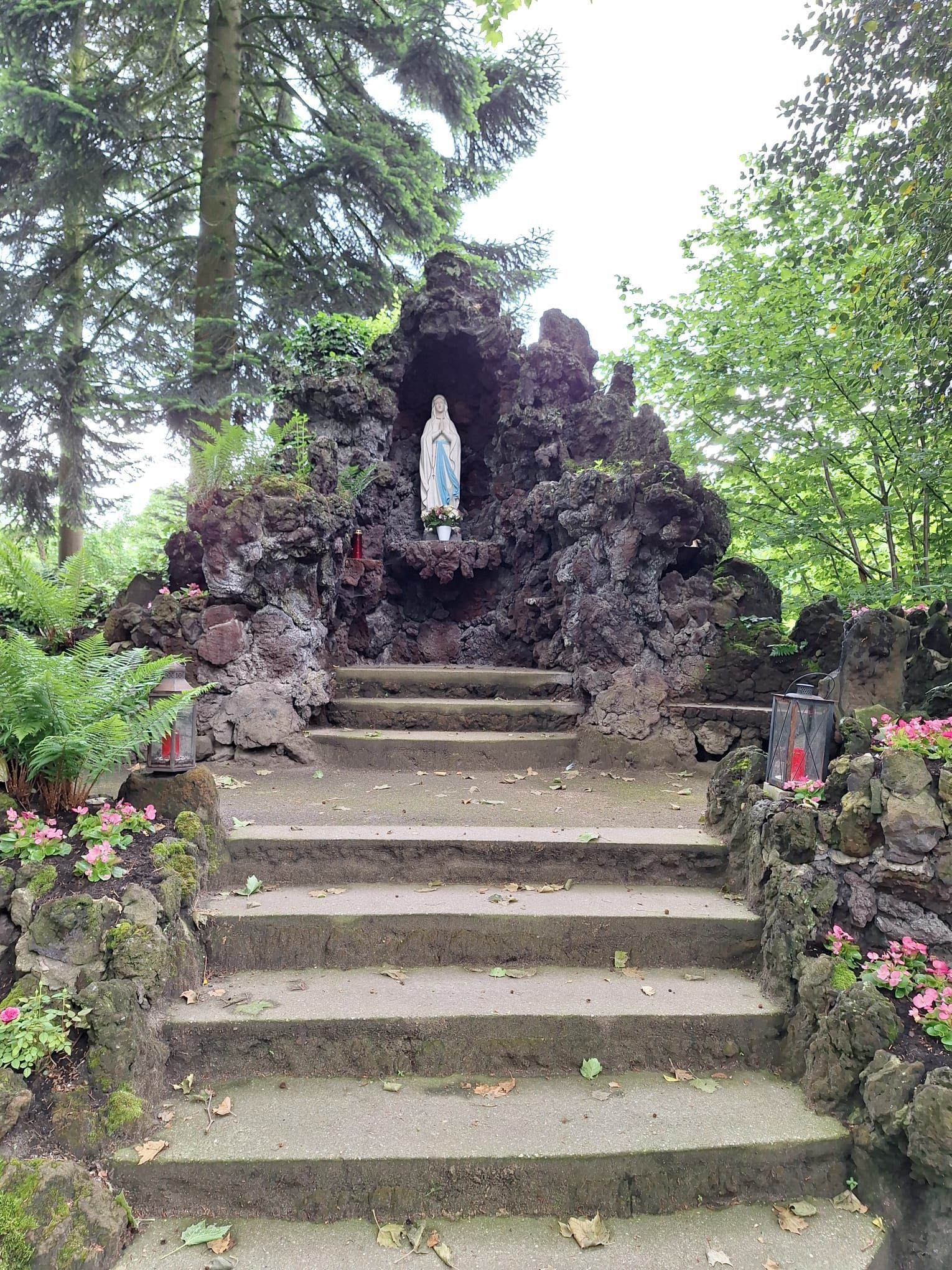 Inmitten einer Felsformation steht eine Marienstatue.