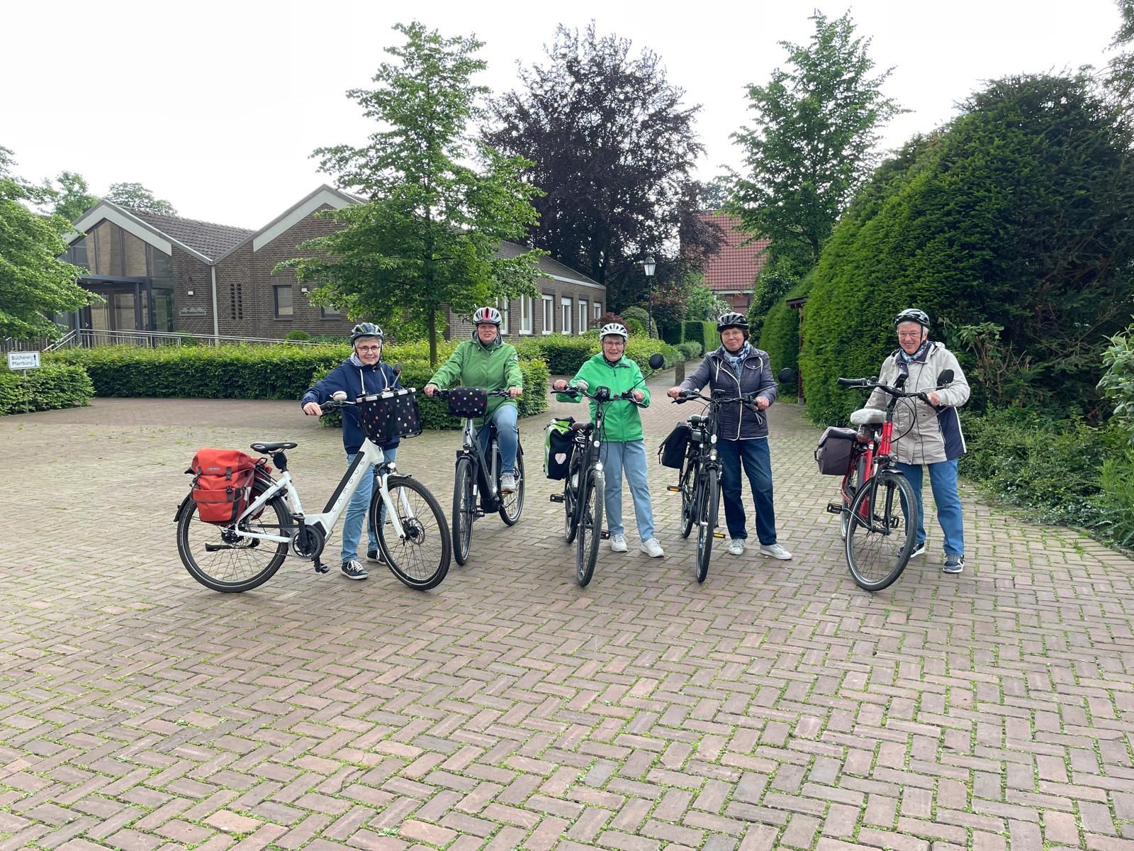 Eine Gruppe von Menschen steht nebeneinander auf Fahrrädern.
