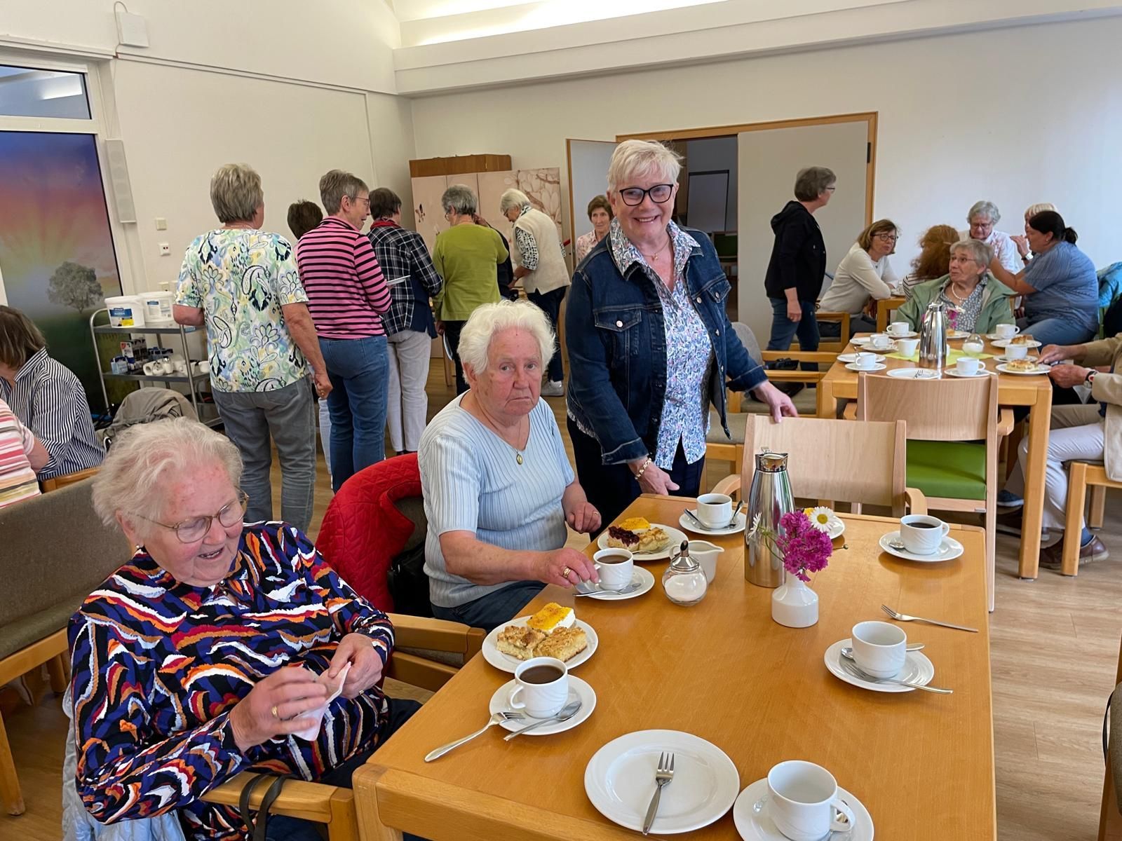 Eine Gruppe von Menschen sitzt in einem Raum an Tischen und isst.