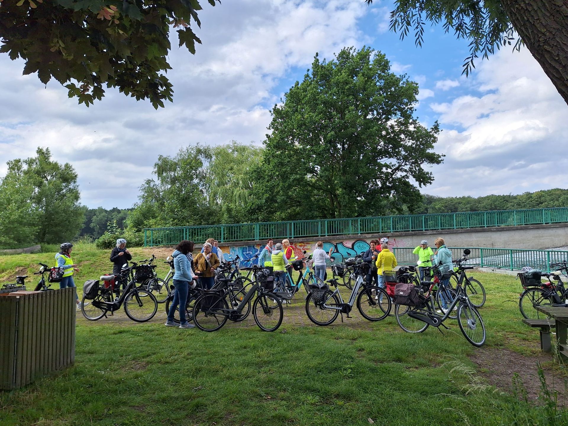 Eine Gruppe von Menschen steht mit Fahrrädern auf einem Feld.