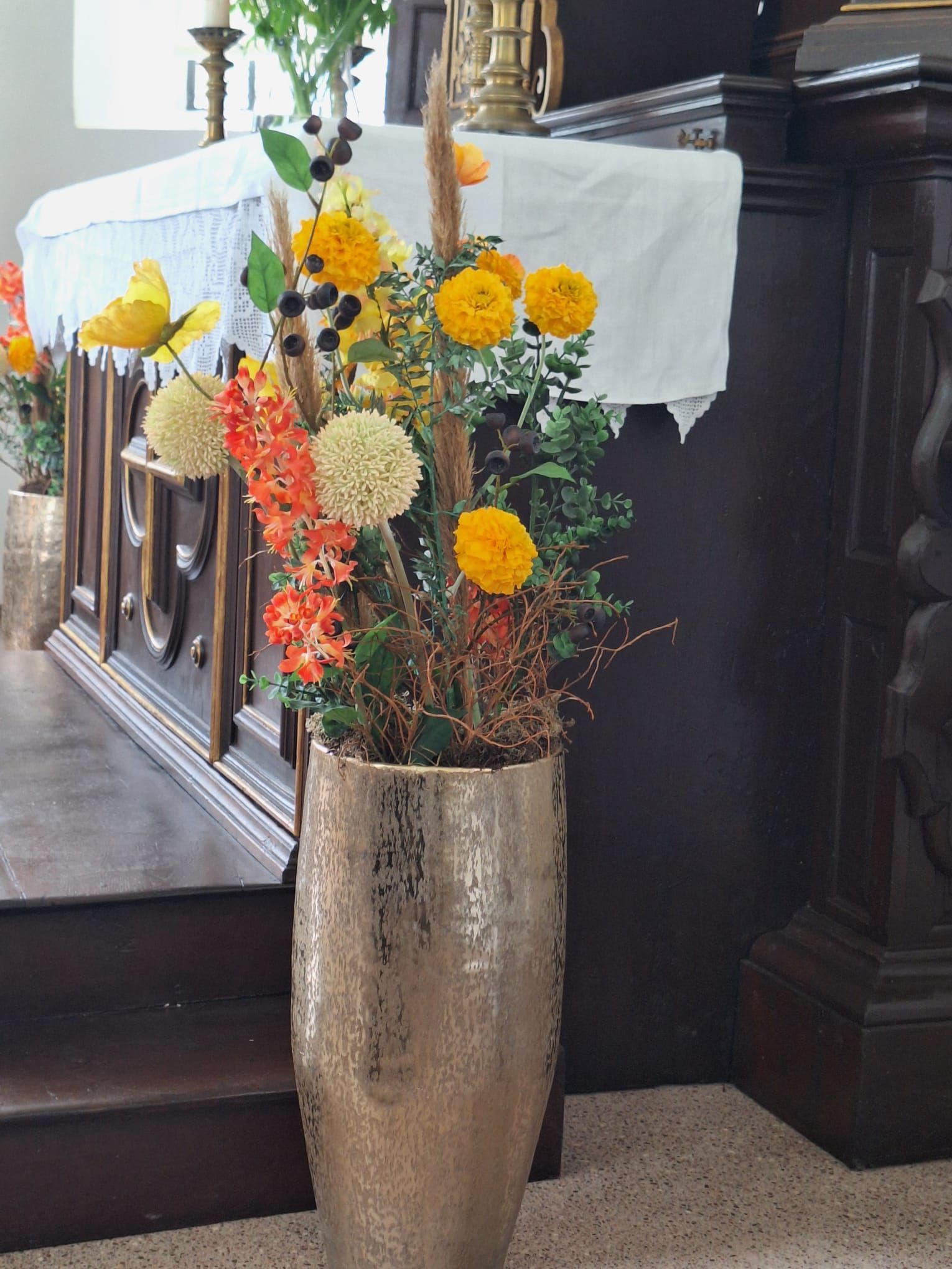 Eine mit Blumen gefüllte Vase steht vor einem Altar