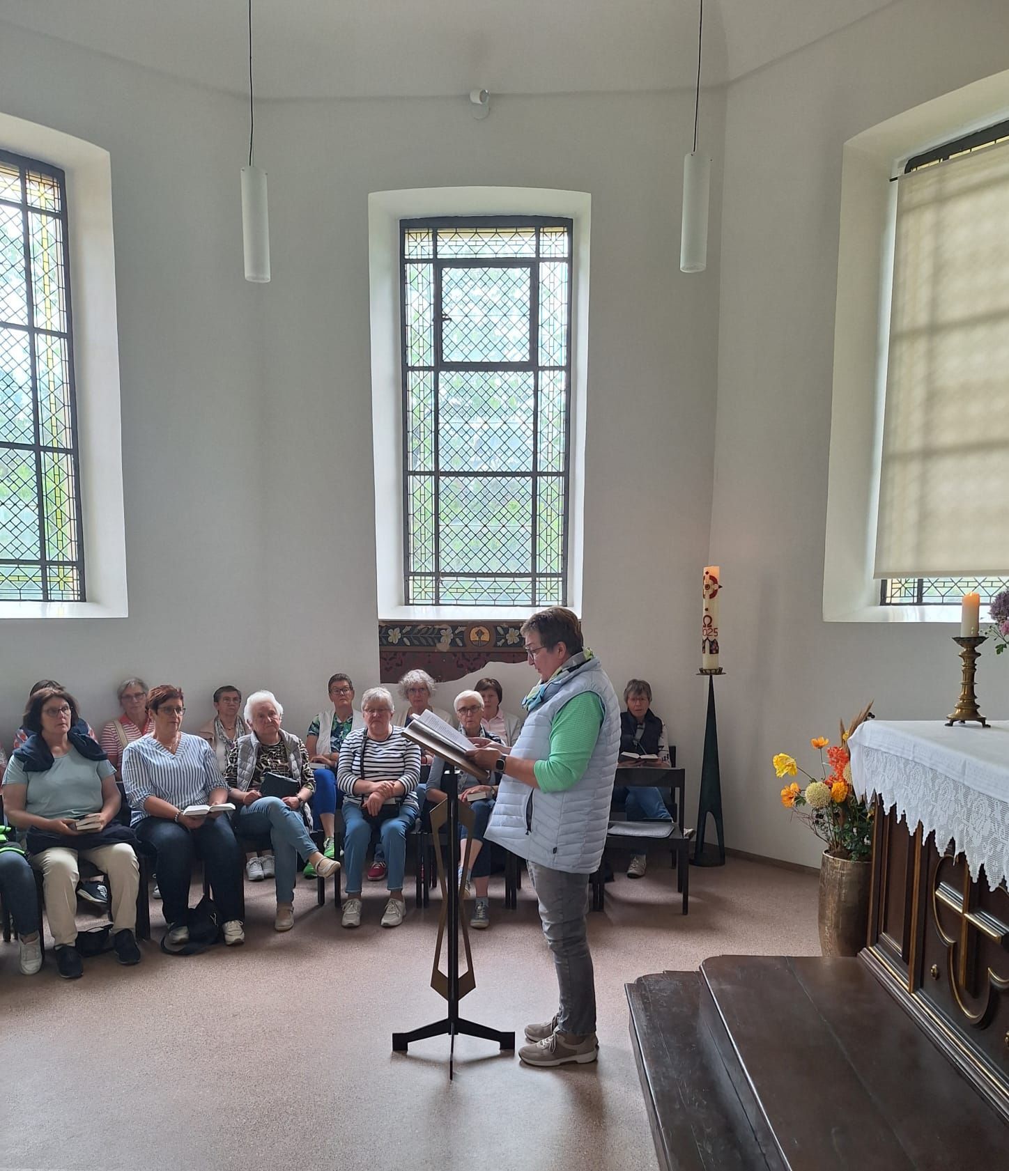 Eine Frau steht vor einer Gruppe von Menschen, die in einer Kirche sitzen.