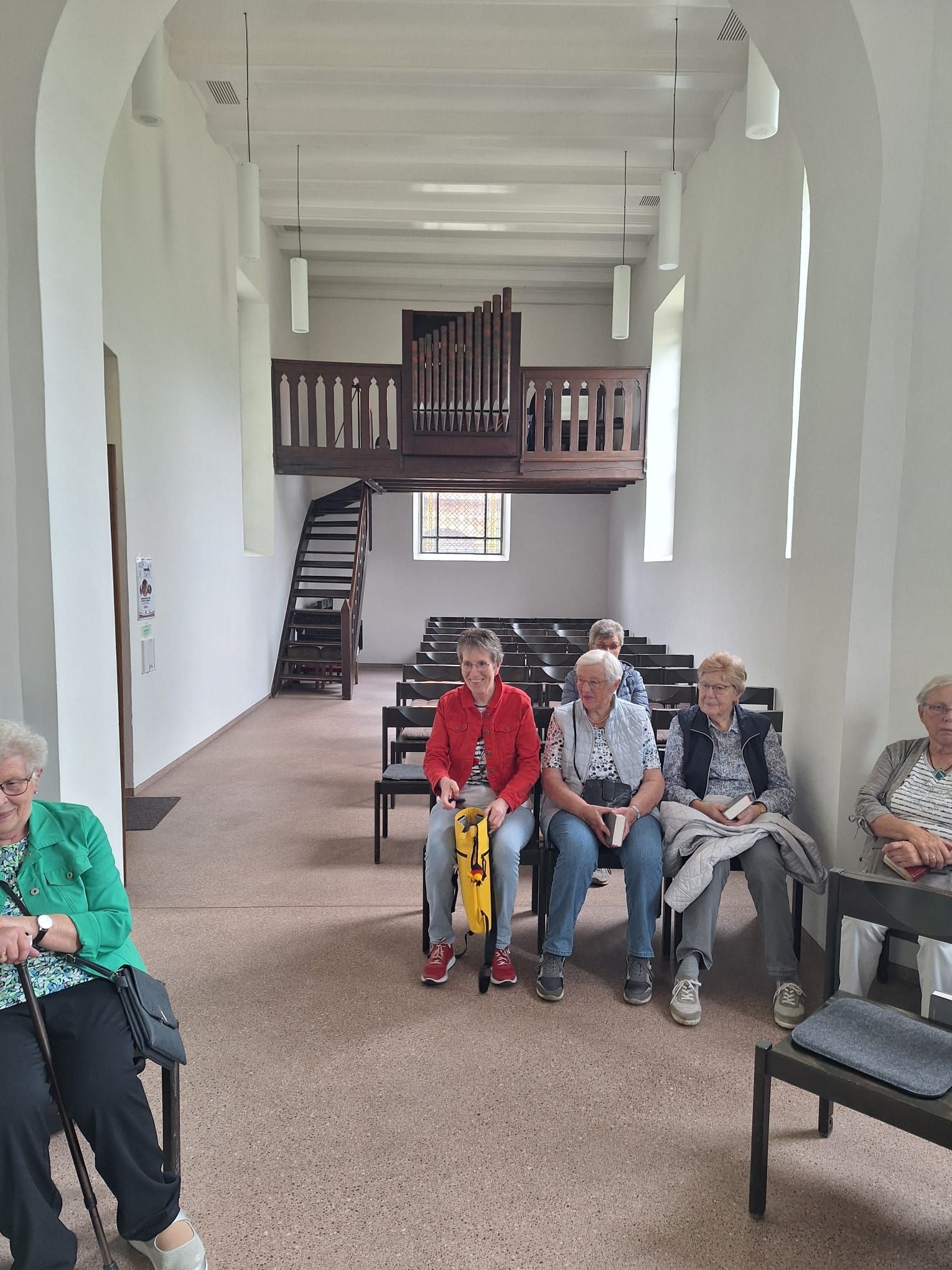 Eine Gruppe von Menschen sitzt in einer Kirche mit Treppen im Hintergrund